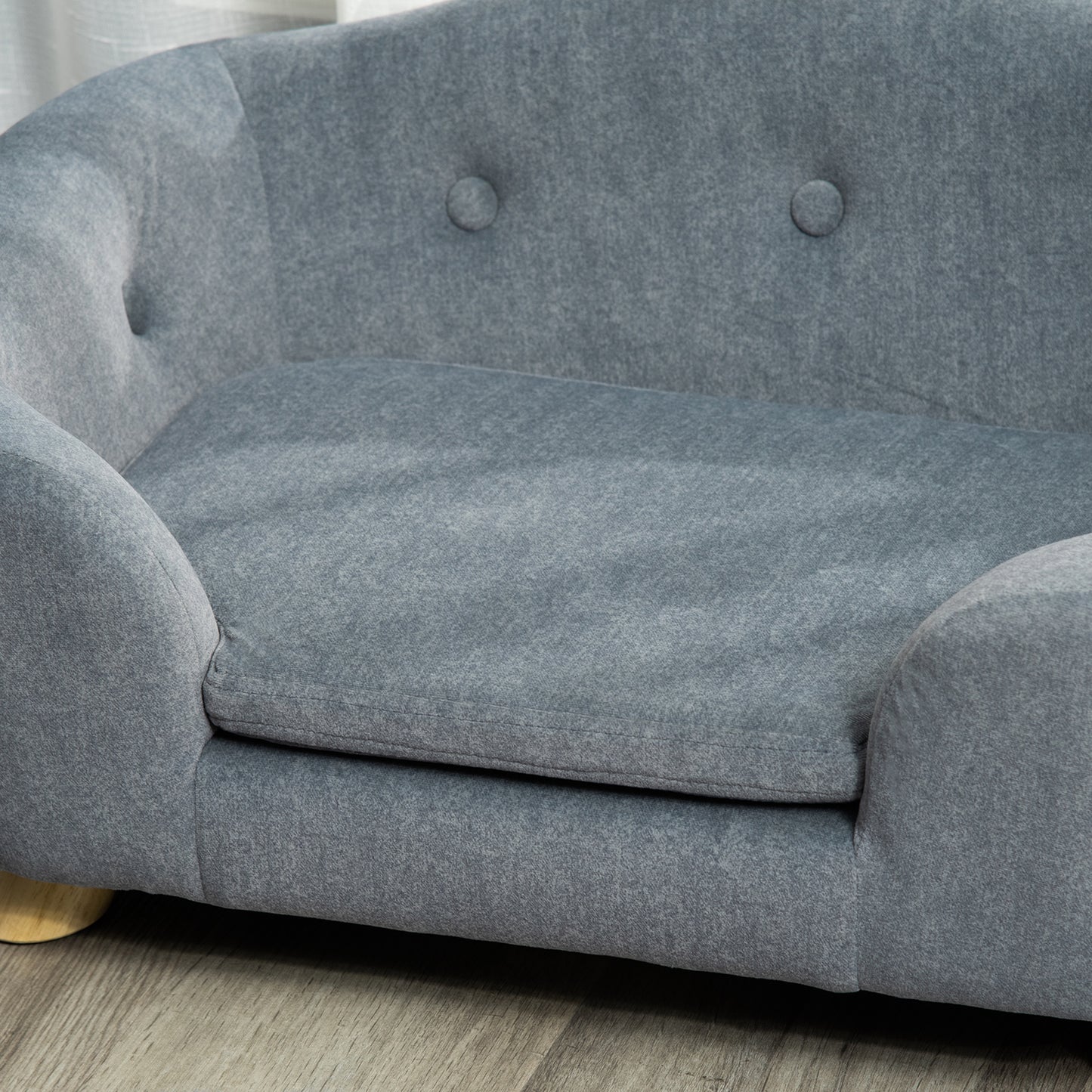 Gray upholstered dog couch with button tufting and wooden legs