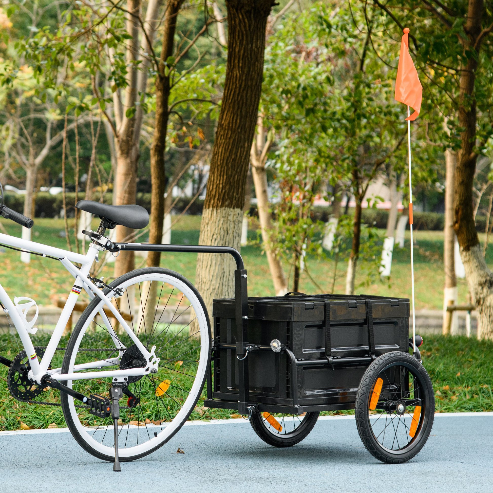 Black folding bicycle cargo trailer with orange safety flag and reflectors