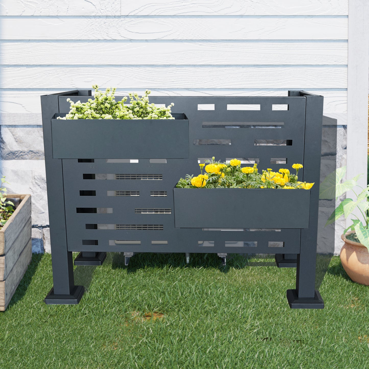 Dark gray metal raised garden planter with white and yellow flowers on grass