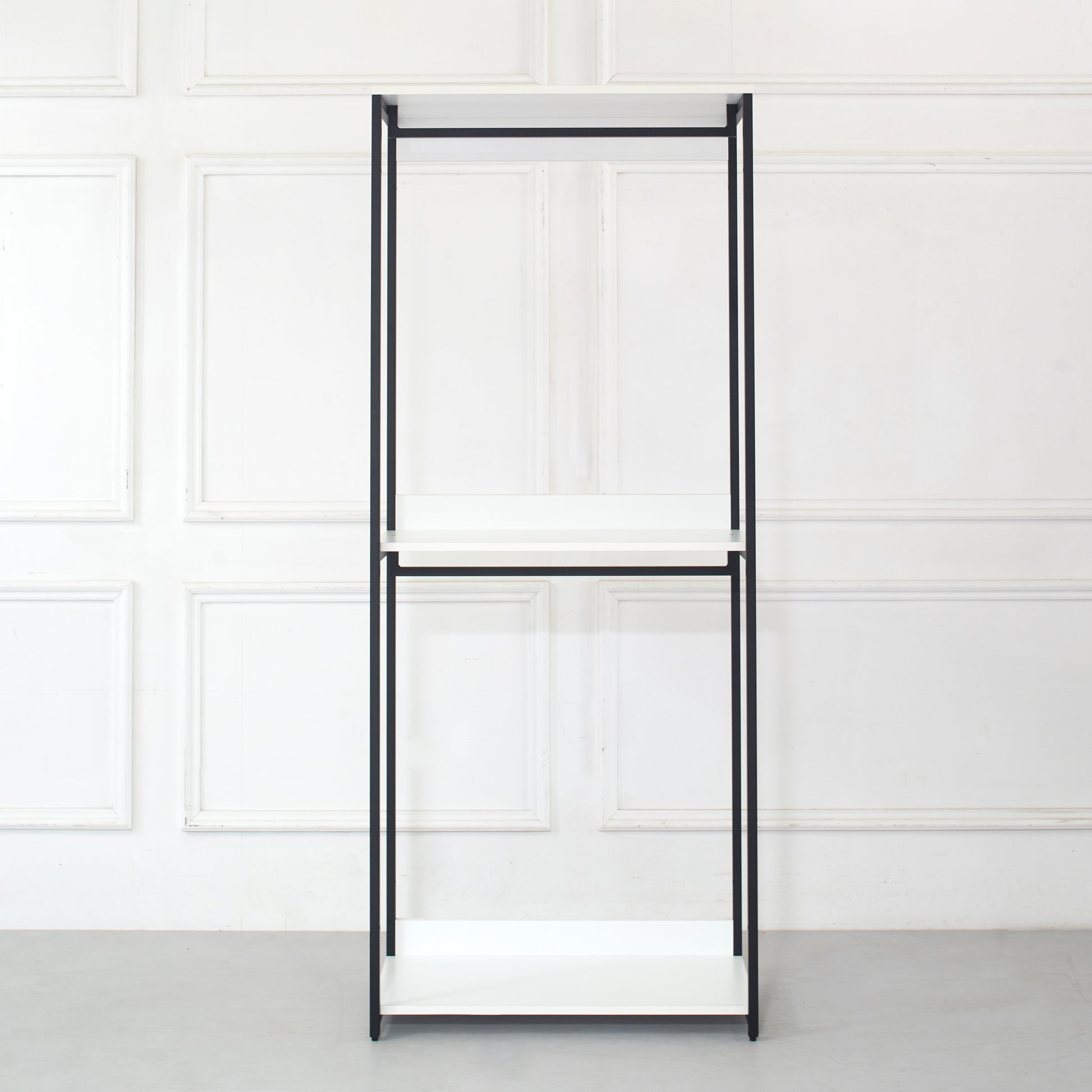 Minimalist black metal clothing rack with three white shelves