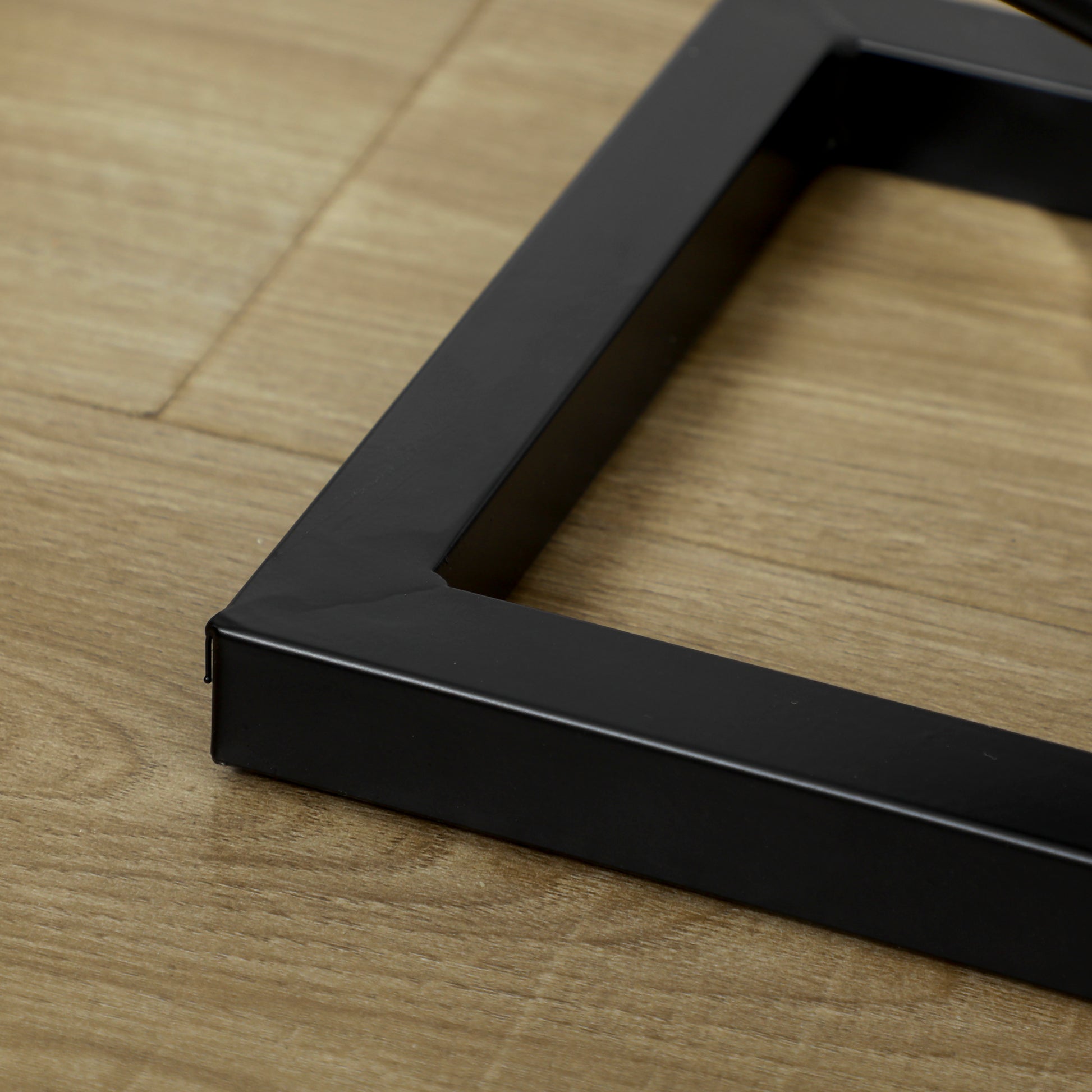 Black metal desk frame corner with wood grain floor