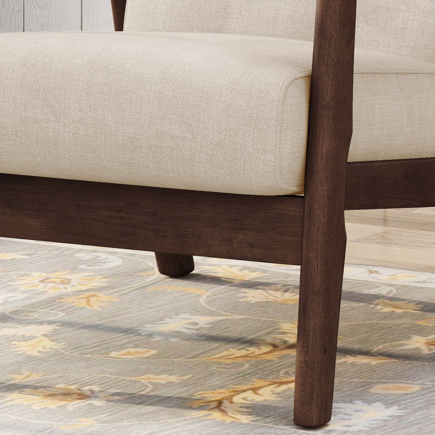 Closeup of a beige upholstered armchair armrest with dark wood frame and legs