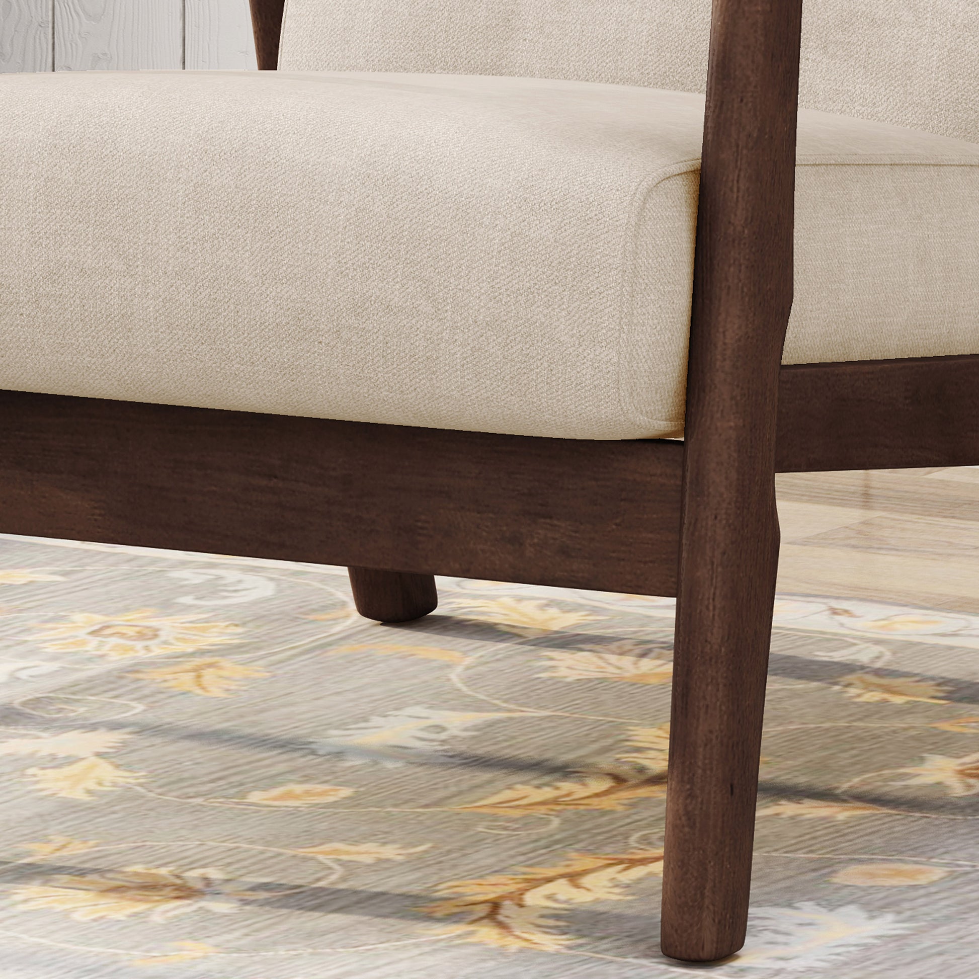 Closeup of a beige upholstered armchair armrest with dark wood frame and legs