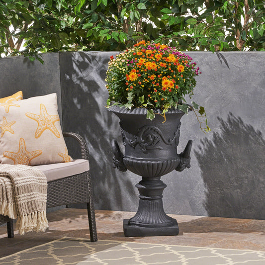 Elaborate black urn planter with ornate handles holding vibrant autumn mums for outdoor decor