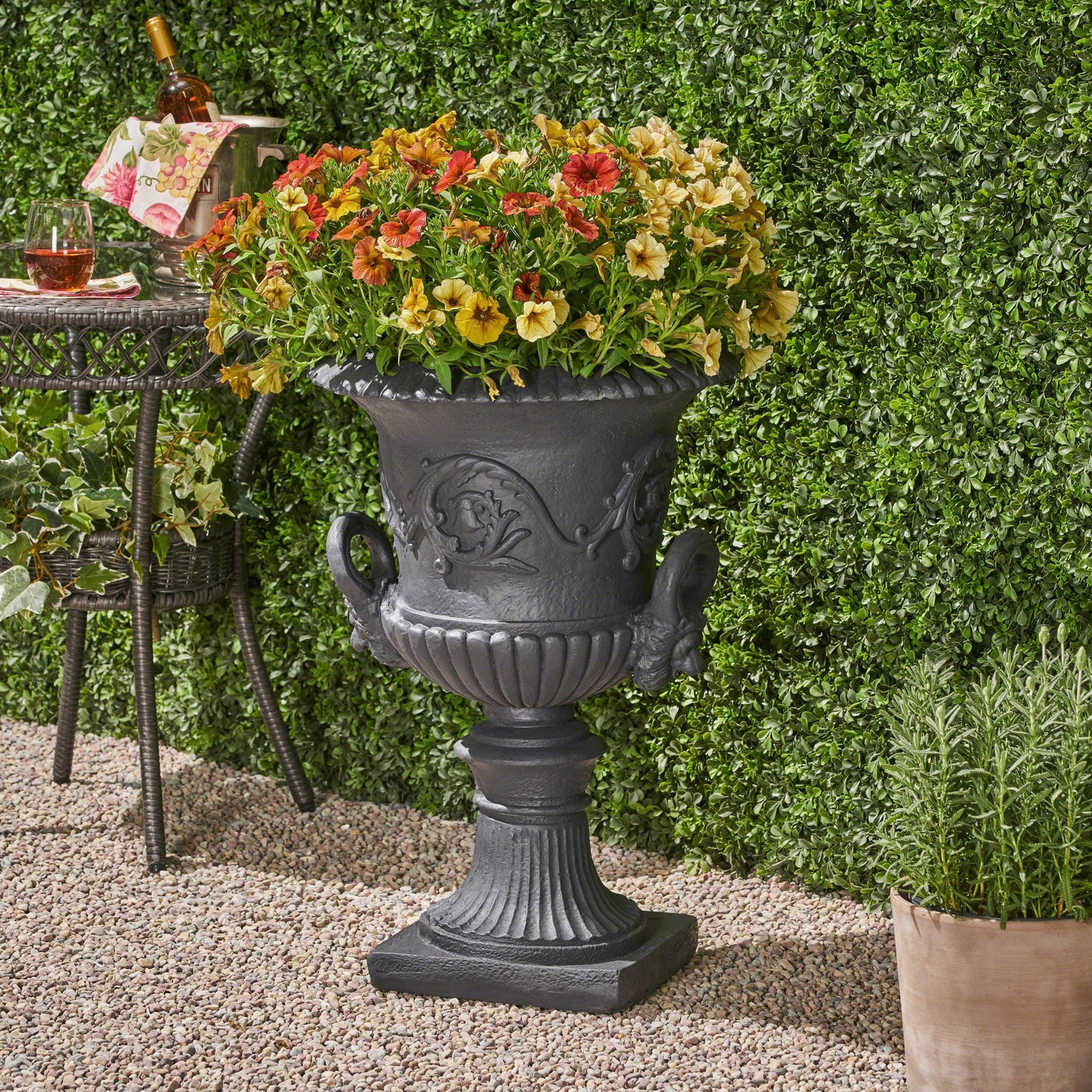 Ornate dark gray cast iron urn planter overflowing with vibrant petunias