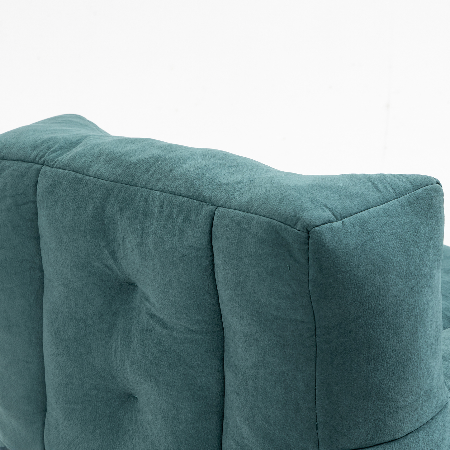 Closeup of a teal velvet tufted armchairs backrest with plush cushioning