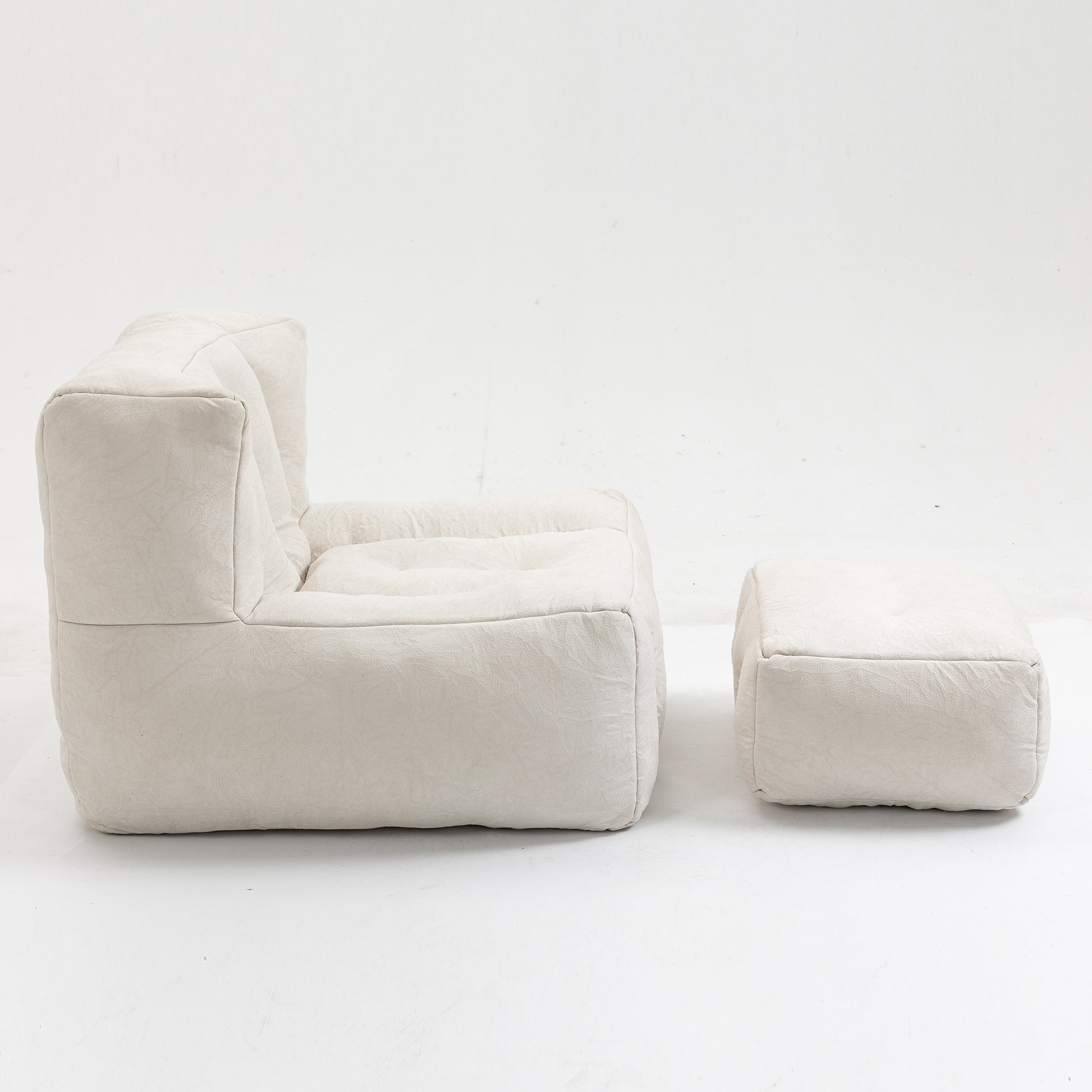 Cream fabric armchair and matching ottoman in a minimalist living room setting