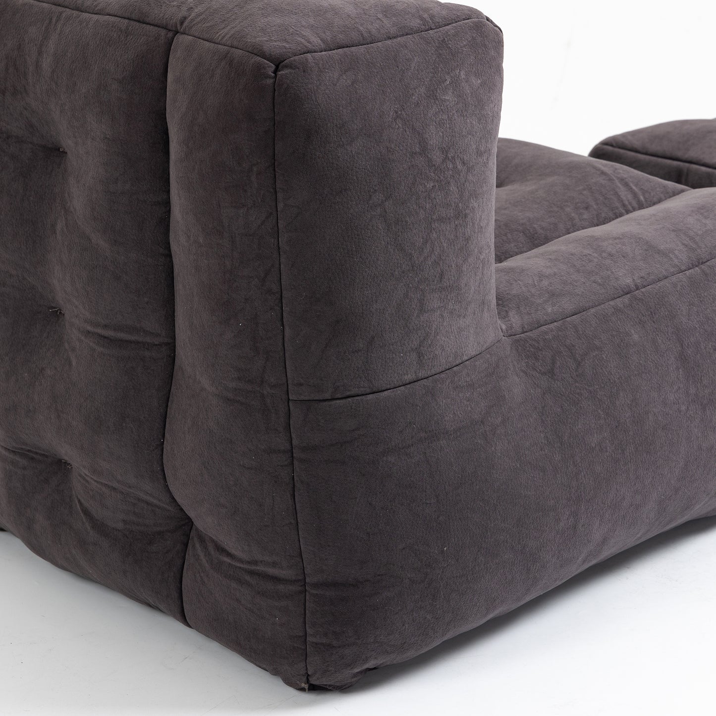 Closeup of a plush charcoal gray armchair showing tufted detailing and soft fabric texture