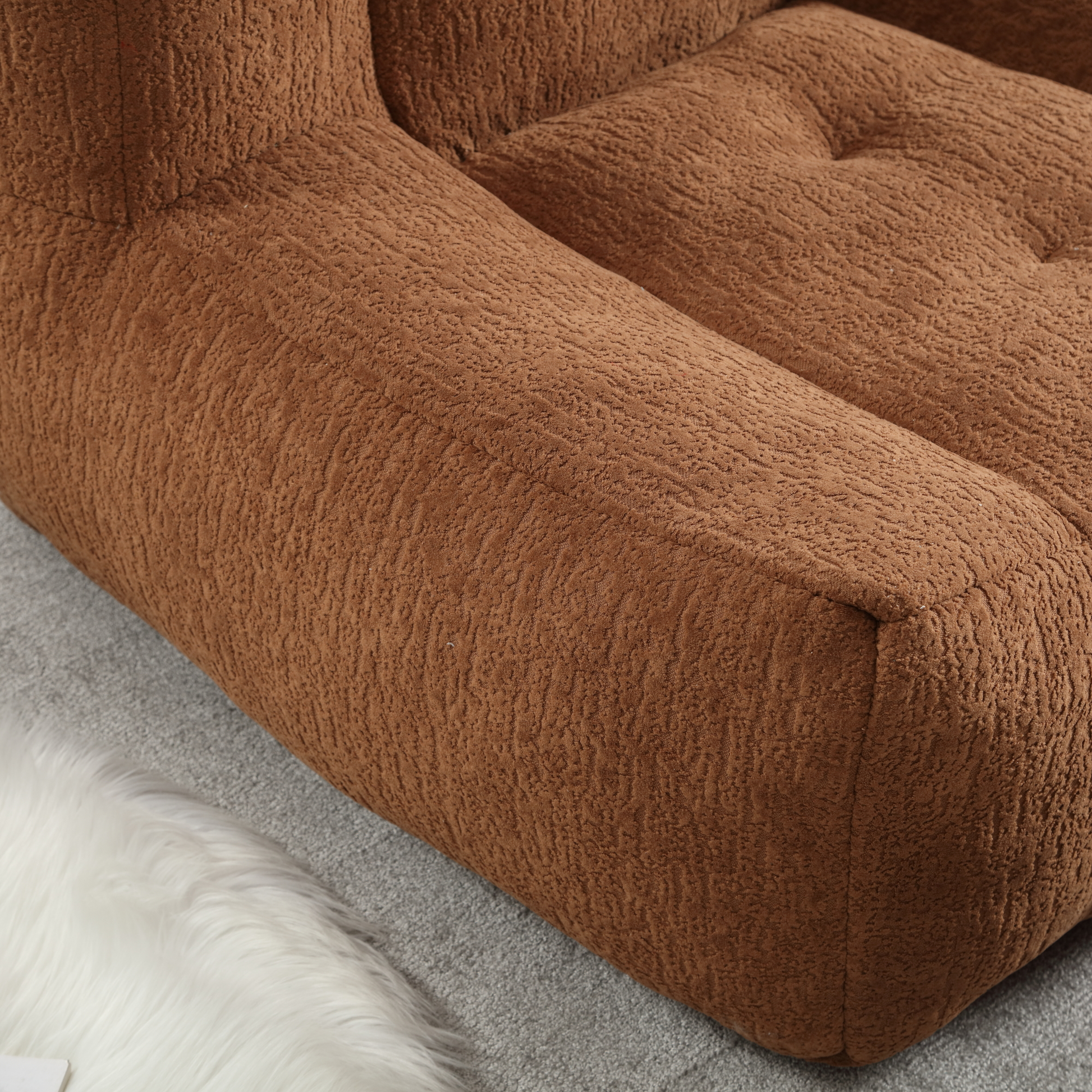 Brown boucle textured armrest on a modern sofa tufted detailing