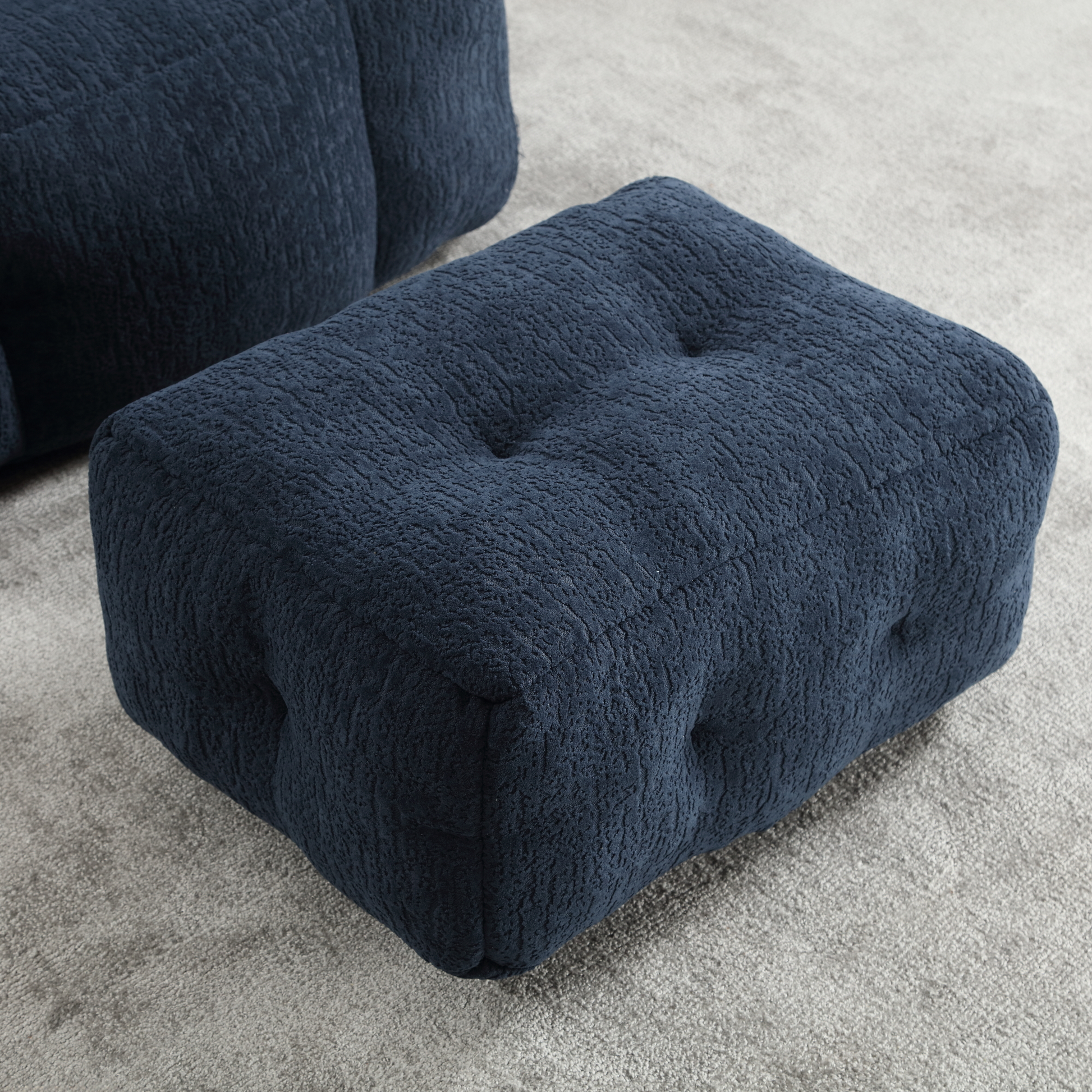 Navy blue upholstered ottoman with textured fabric and tufted design