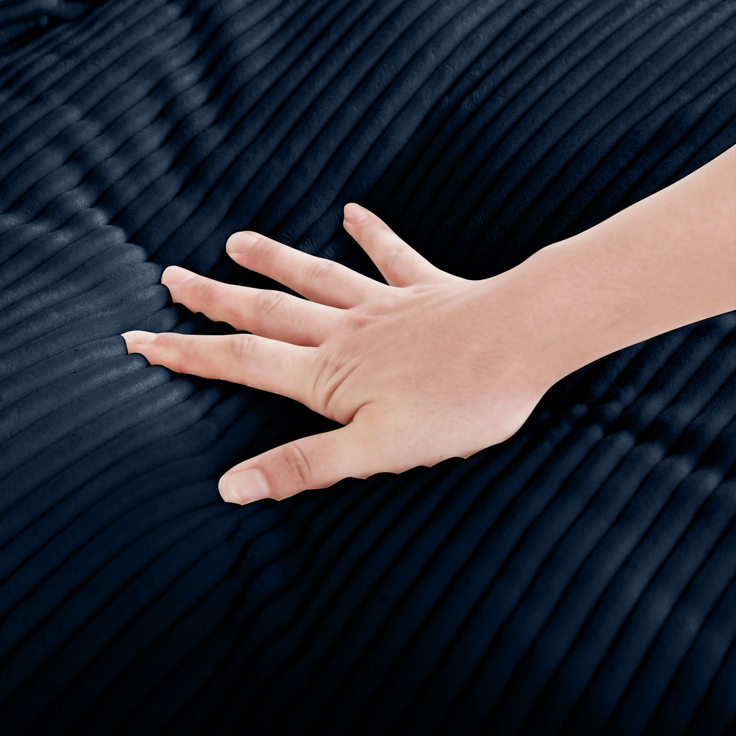 Closeup of hand touching plush navy blue corduroy fabric highlighting soft texture