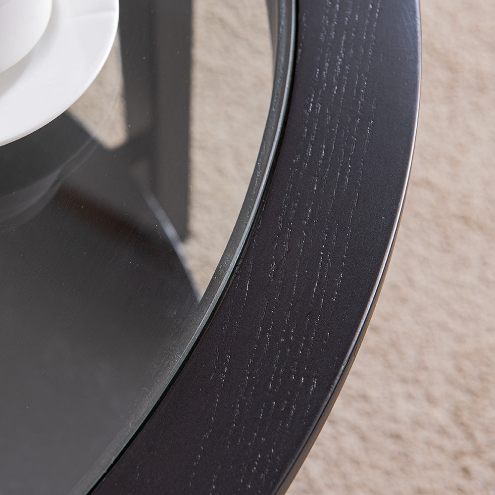 Dark wood round coffee table with a glass top and a textured edge