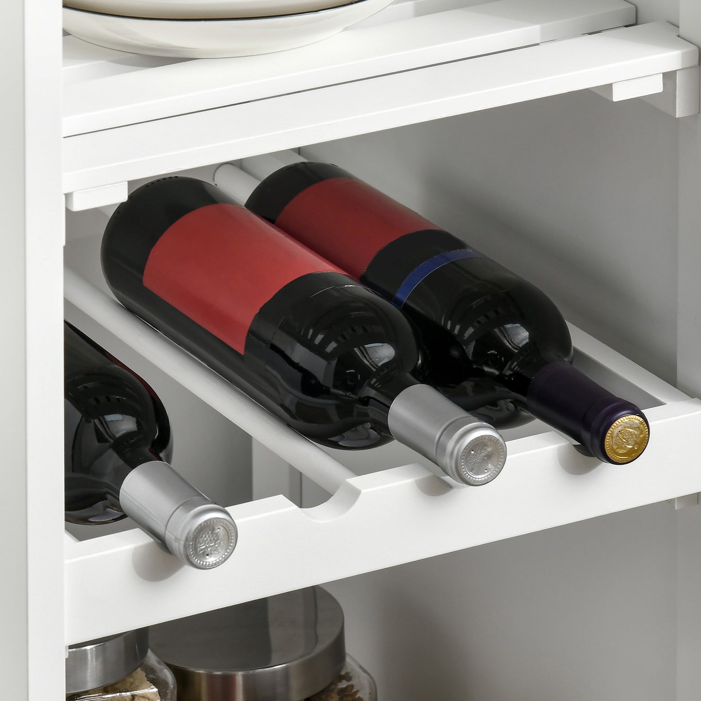 White wine rack holding four red wine bottles with silver caps