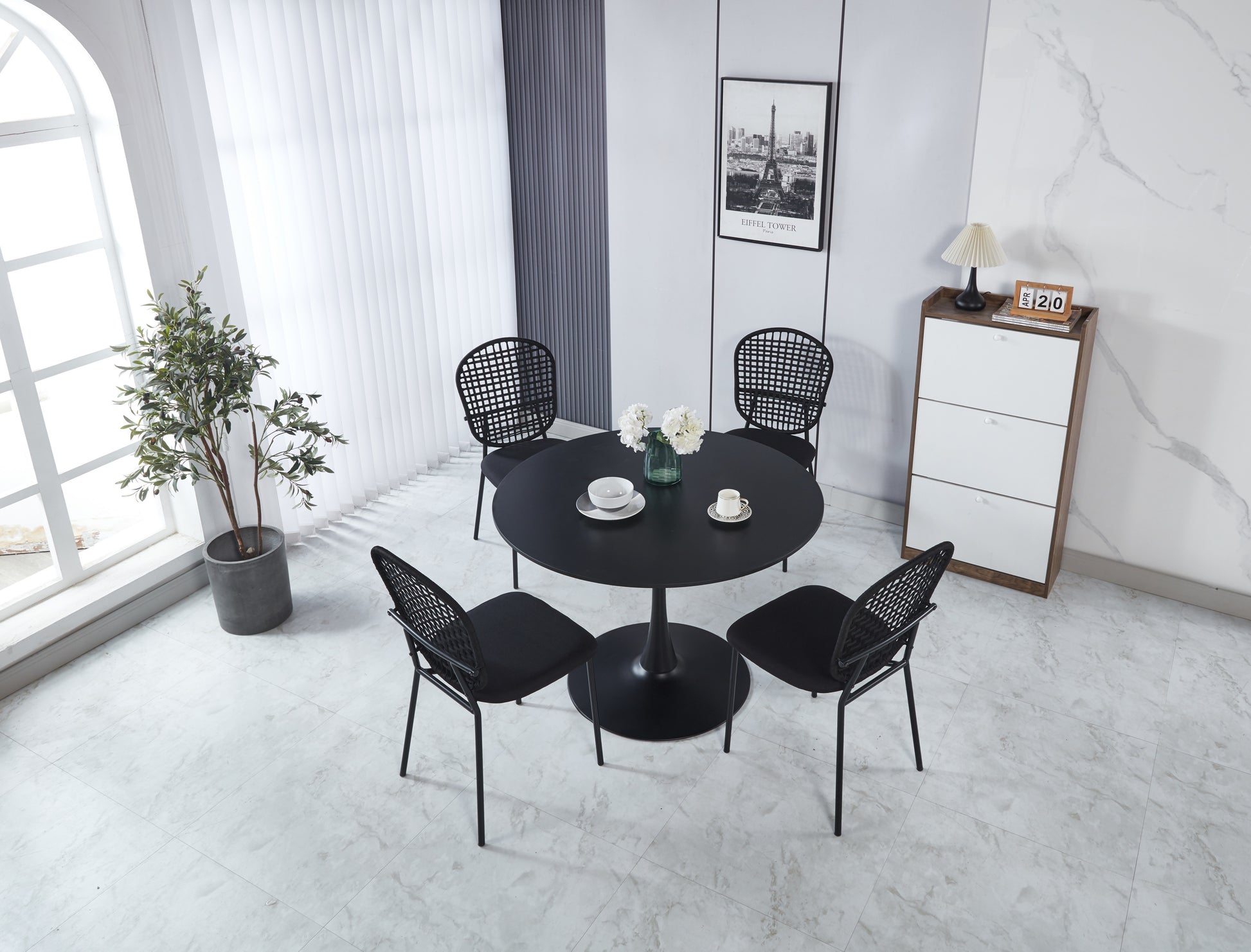 Modern black round dining table with four woven chairs set for dining