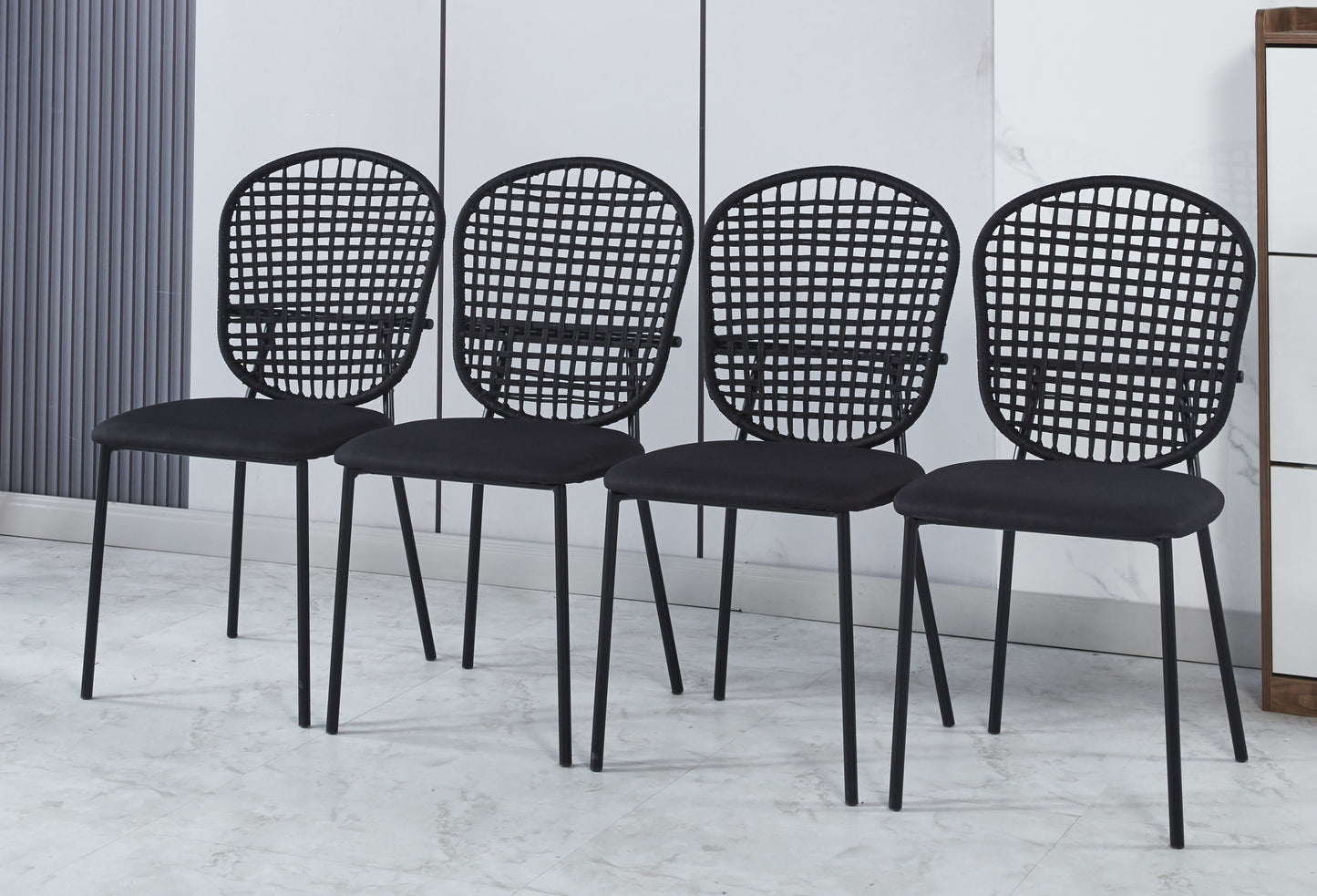 Four black dining chairs with woven backs and upholstered seats
