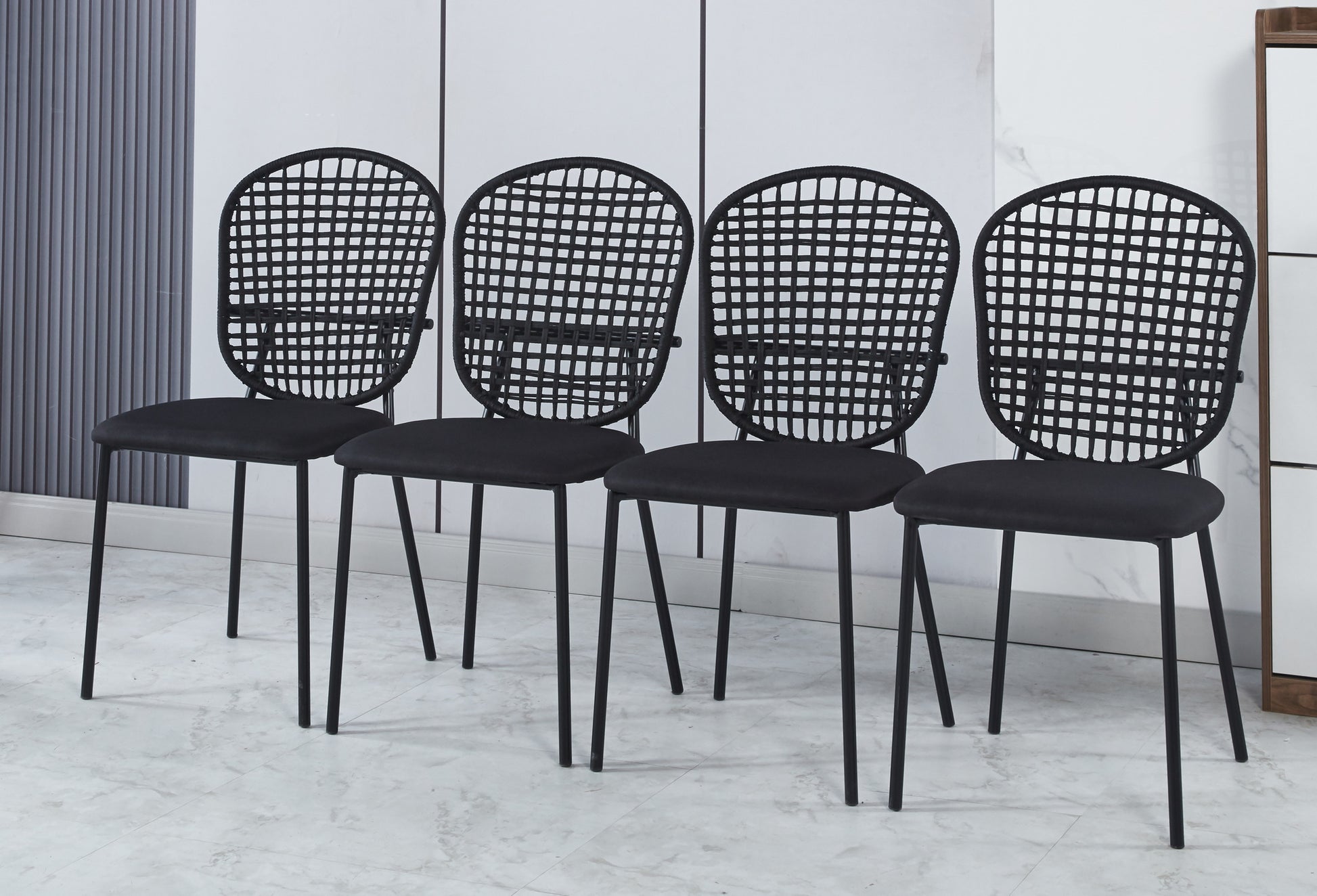 Four black dining chairs with woven backs and upholstered seats