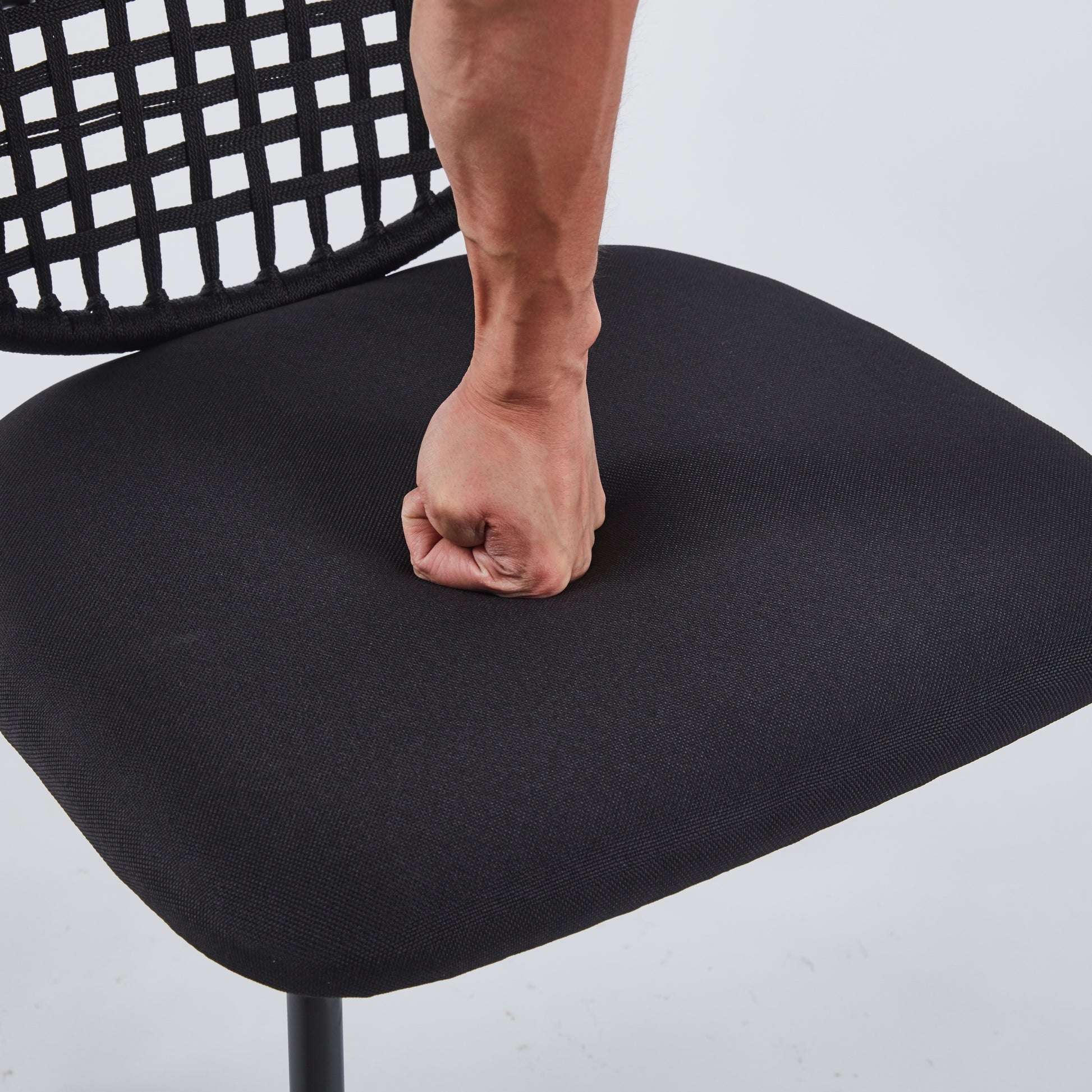 Closeup of a fist pressing into the cushioned seat of a black office chair