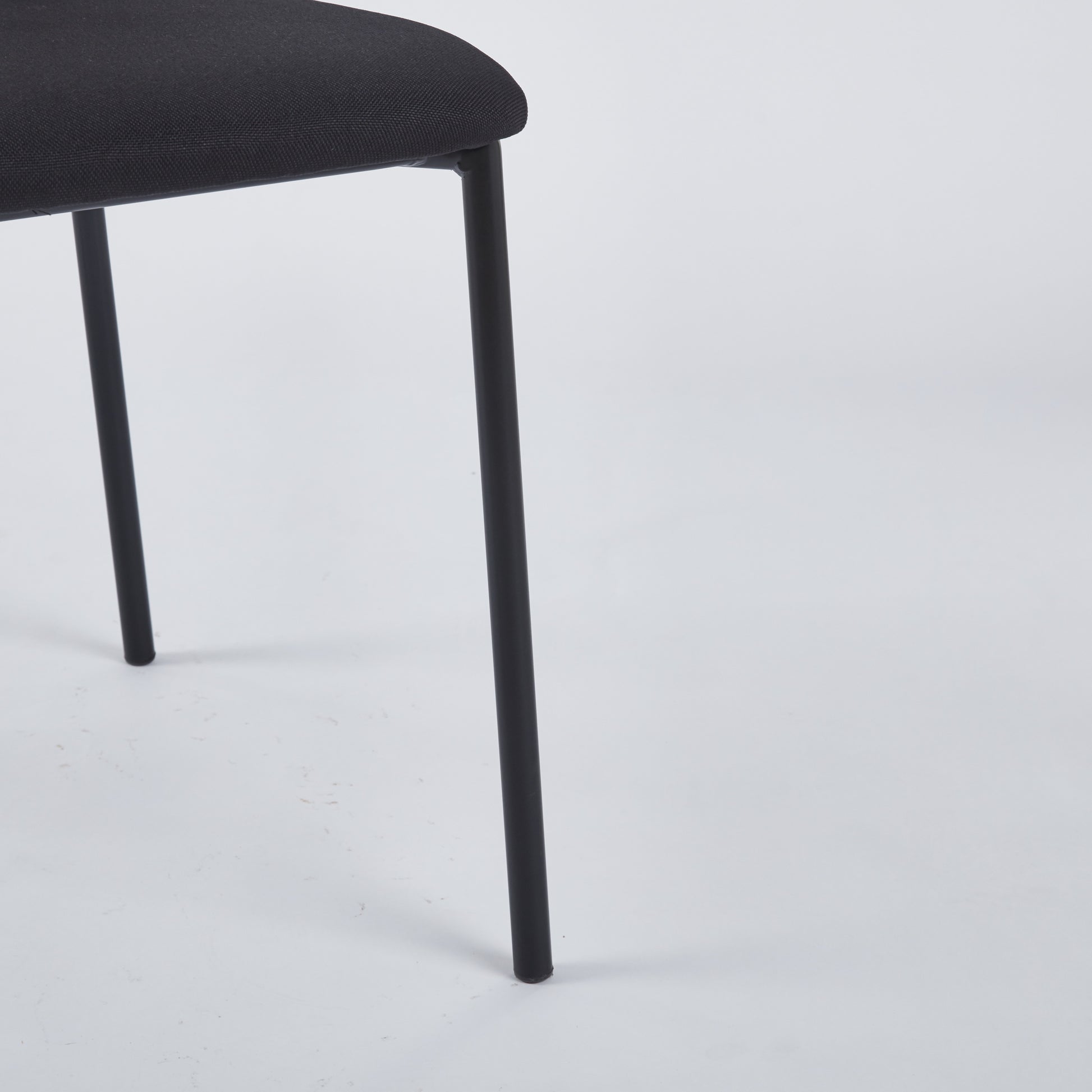 Textured black fabric seat and thin black metal leg of a modern chair