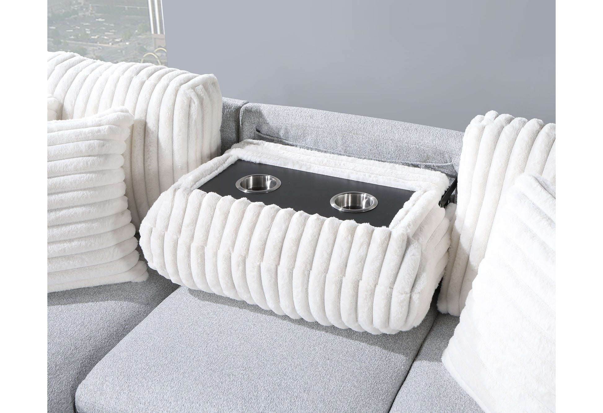 Closeup of a plush white throw pillow with ribbed texture on a light gray sofa with a builtin cup holder tray