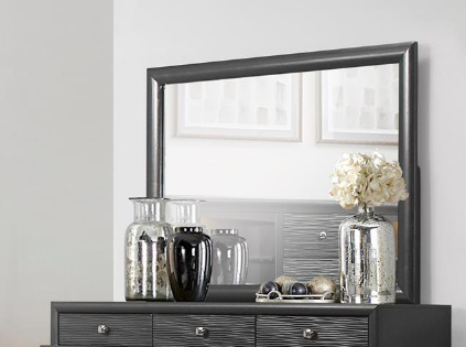Gray dresser with carved drawer fronts and large mirror reflecting artwork
