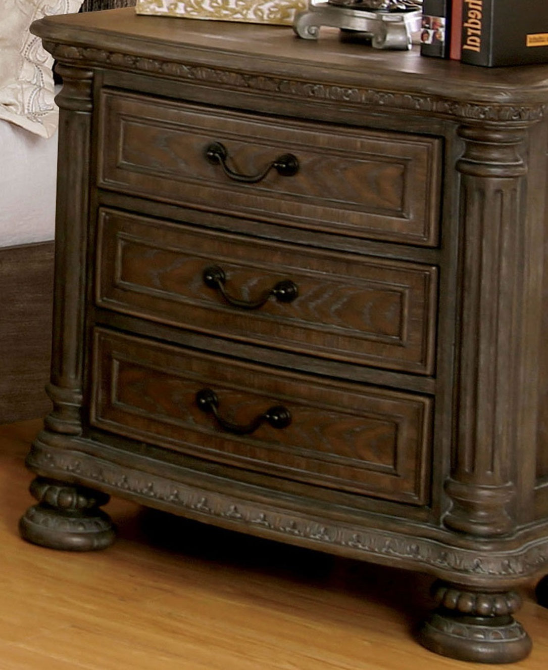 Dark wood nightstand with three drawers and ornate carved details