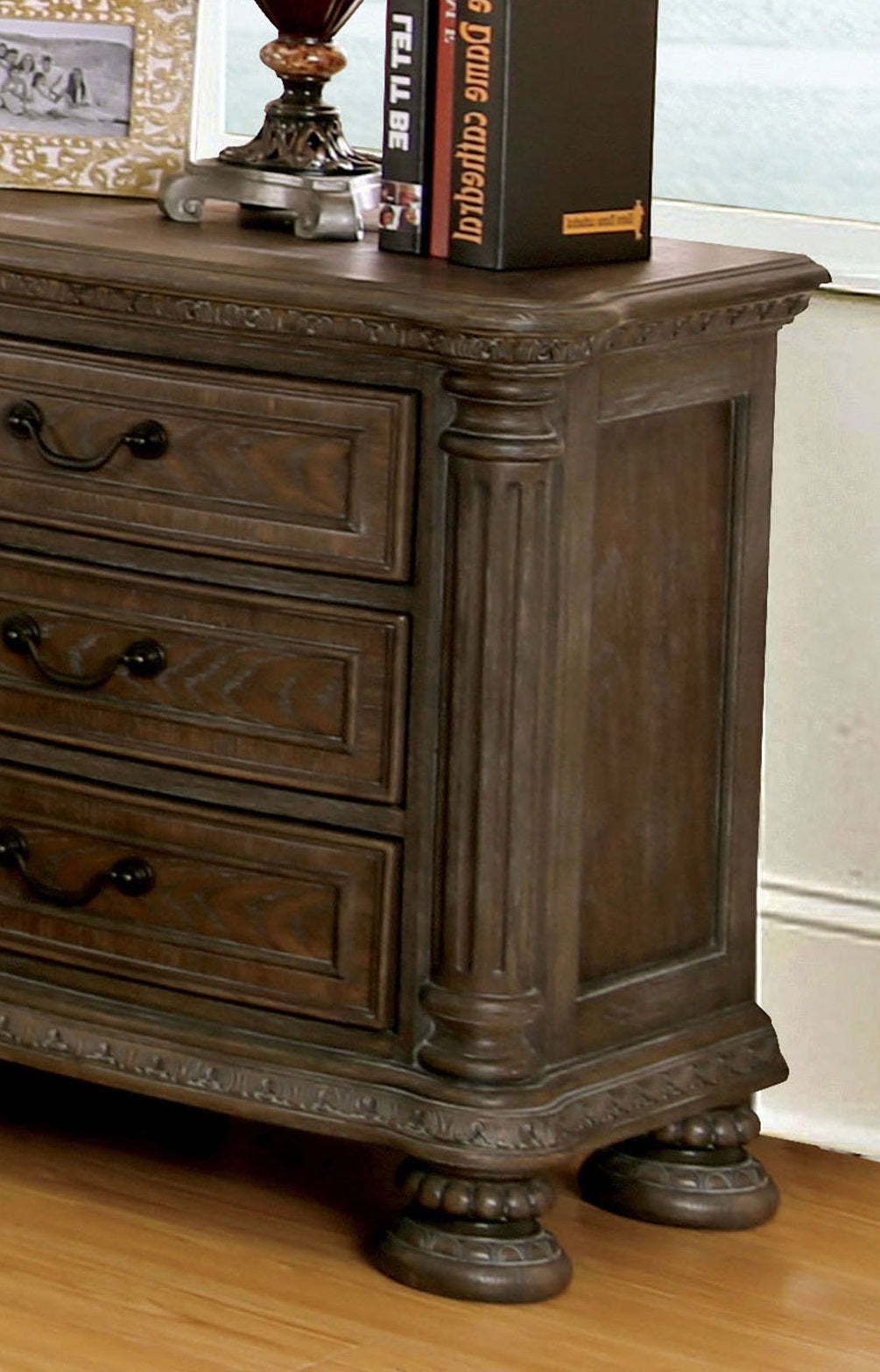 Dark wood dresser with three drawers and ornate carved details on the base