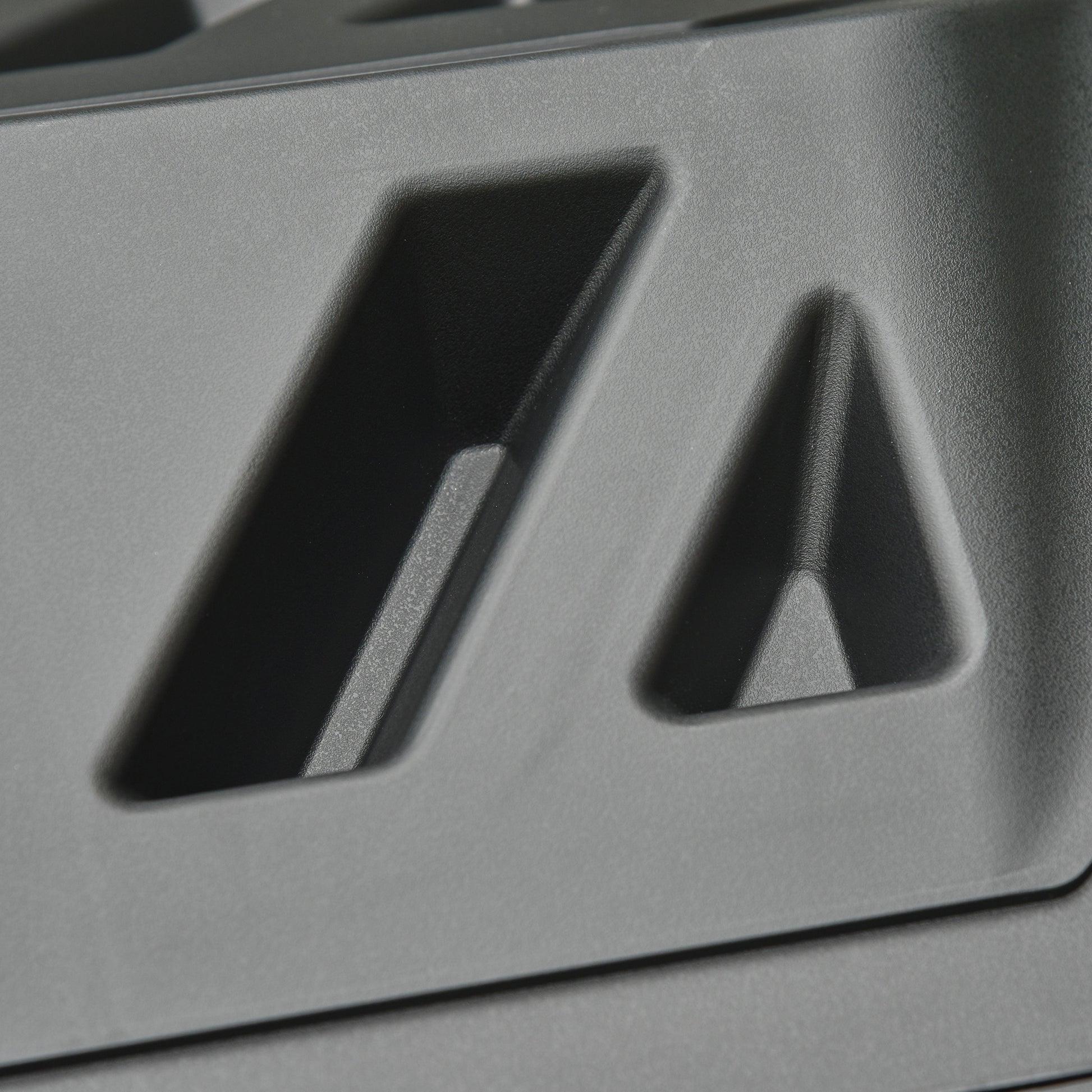 Closeup of a textured dark gray plastic housing with angled cutouts likely for an electronic device