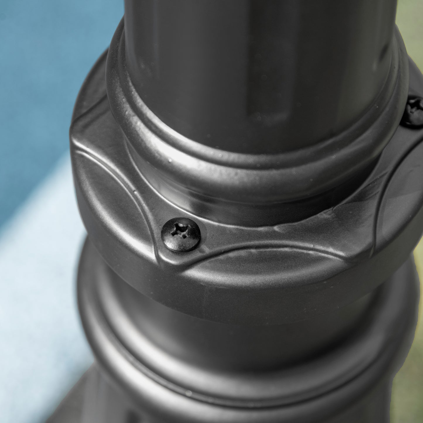 Closeup of a black metal garden umbrella pole joint with visible screw detail