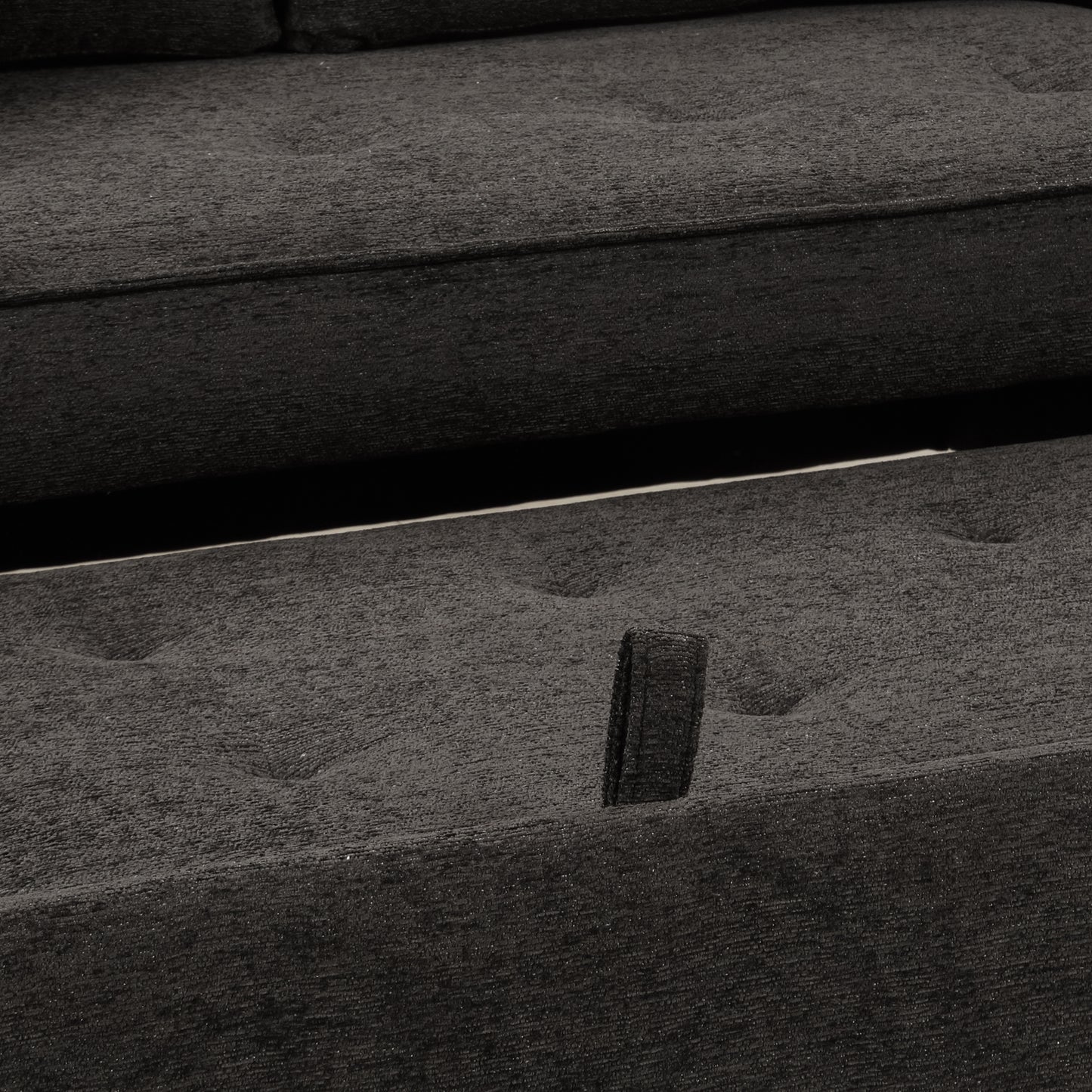 Closeup of textured dark gray sofa fabric with button tufting detail