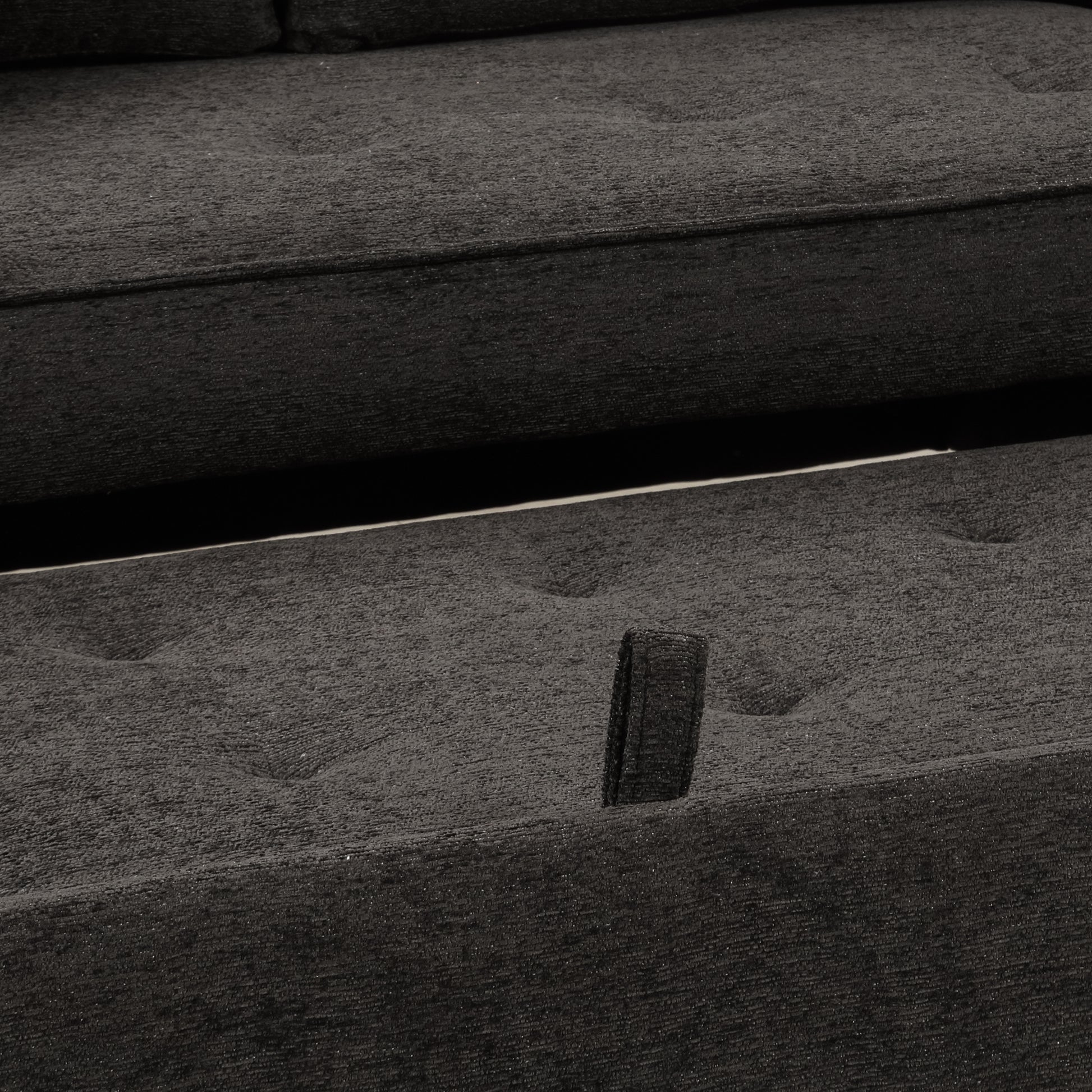 Closeup of textured dark gray sofa fabric with button tufting detail