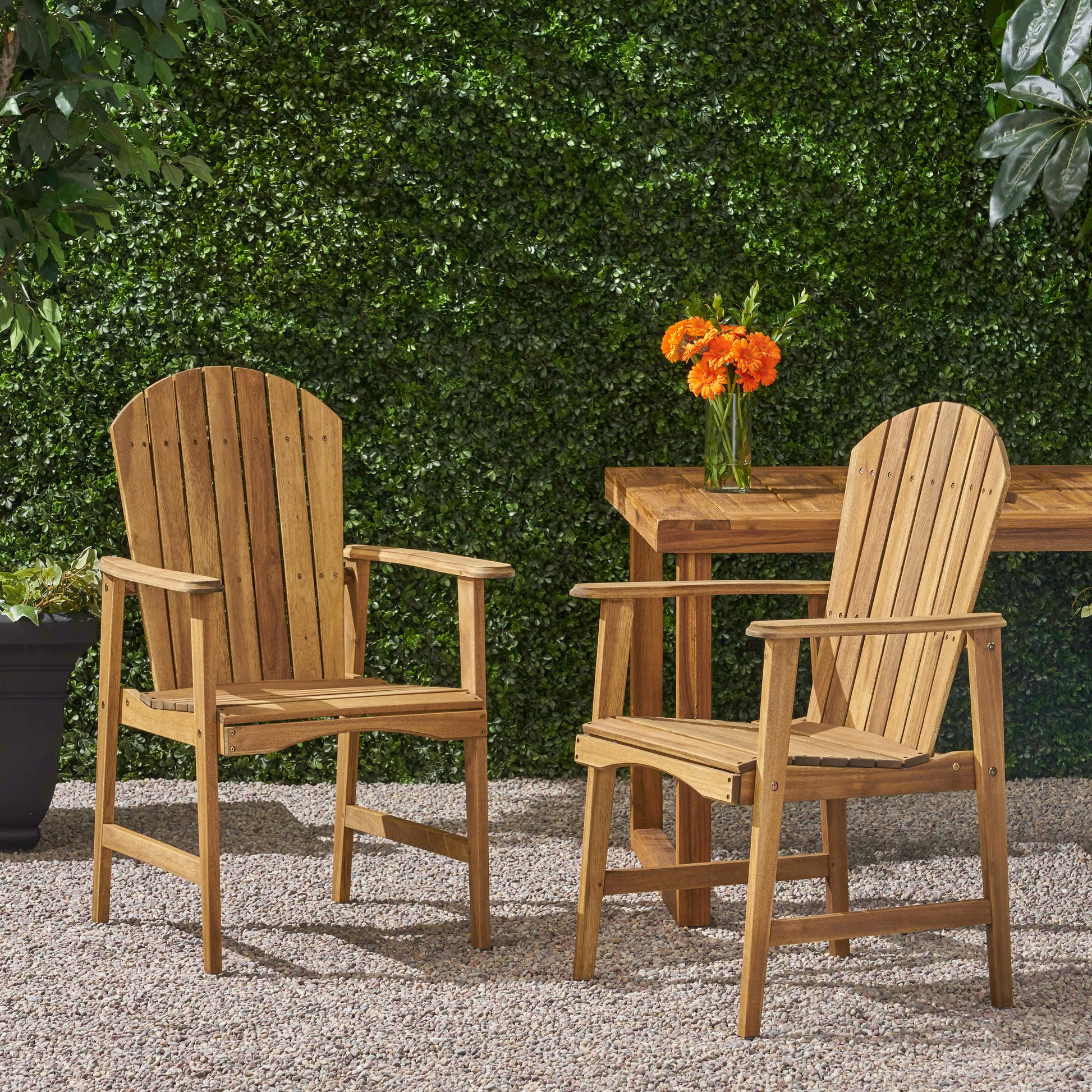 Two natural wood Adirondack chairs with slatted backs and seats arranged on gravel patio