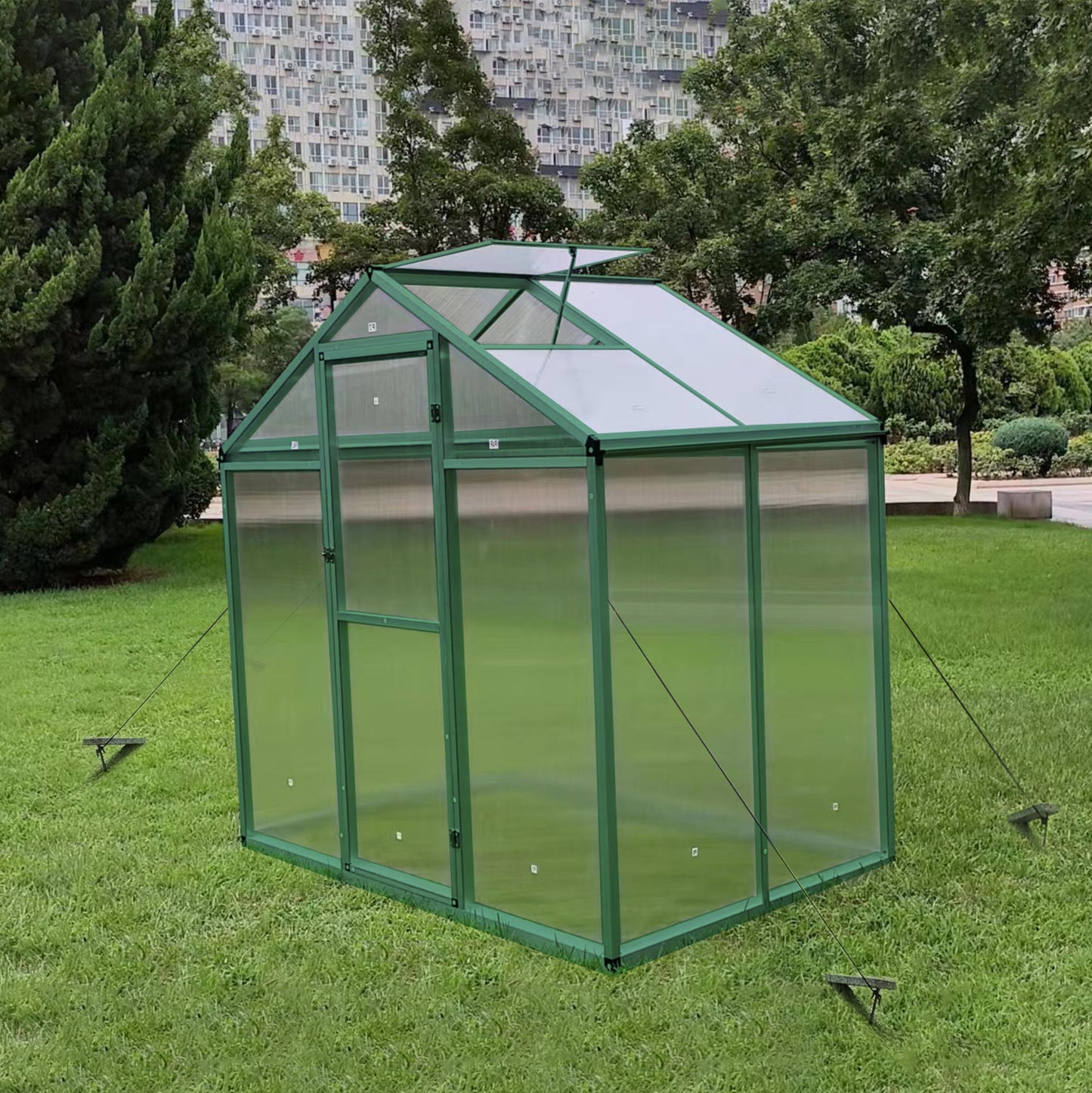 Green metal frame greenhouse with clear polycarbonate panels and a pitched roof