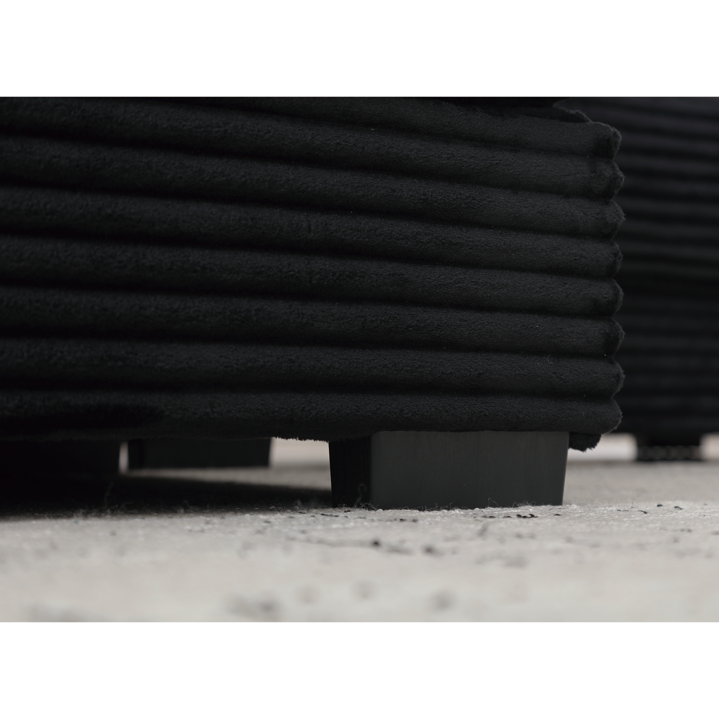 Black corduroy sofa section with plush texture and modern black legs