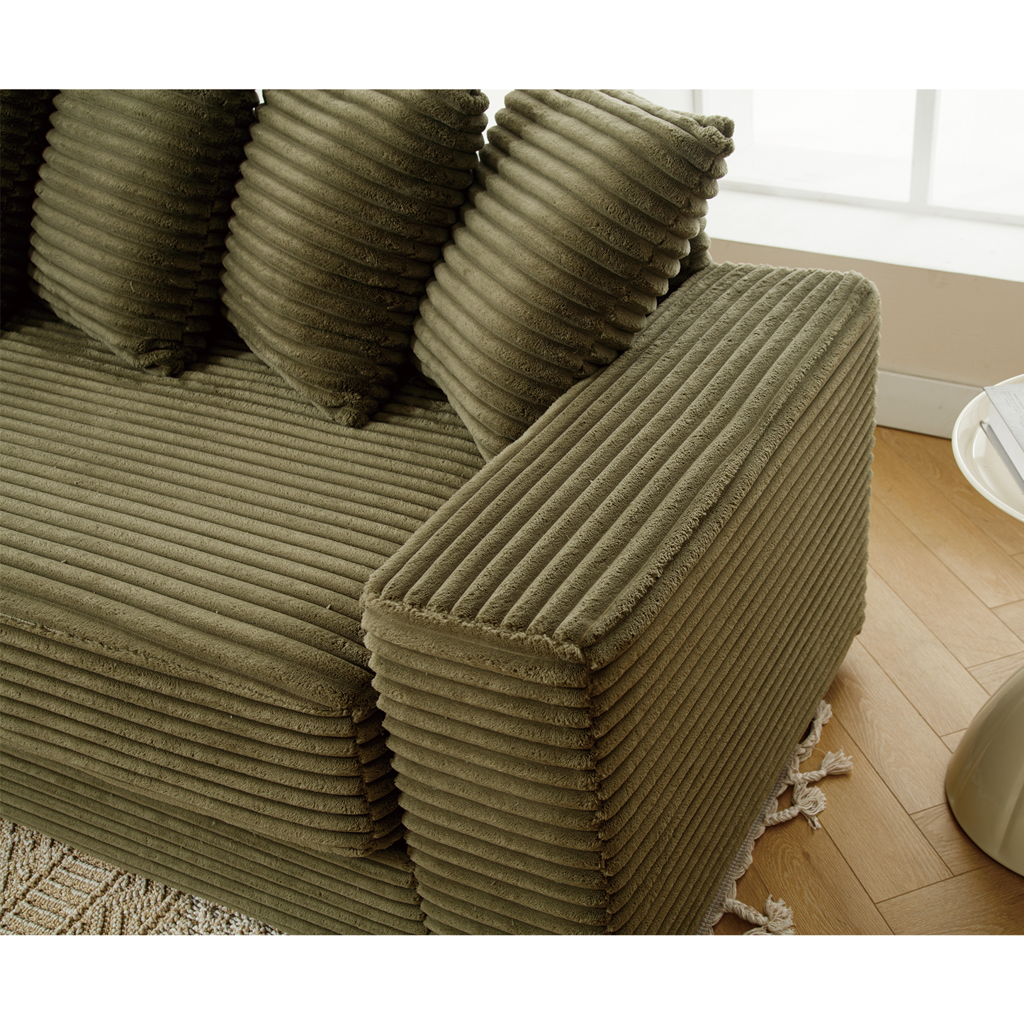 Olive green corduroy sectional sofa with plush cushions and fringe detail on floor