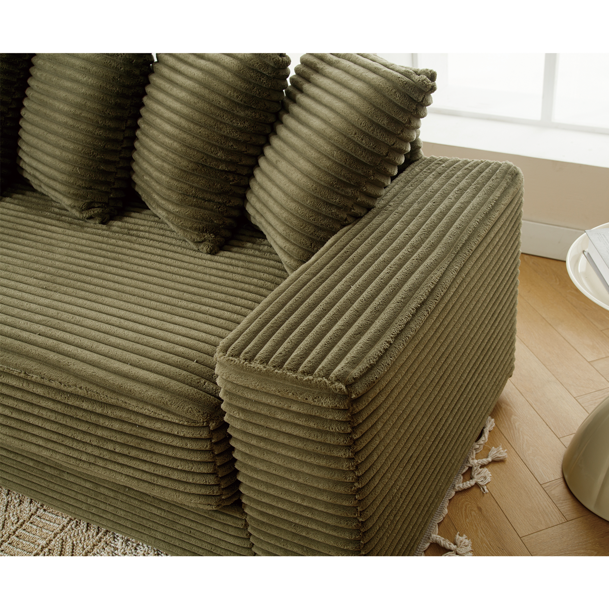 Olive green corduroy sectional sofa with plush cushions and fringe detail on floor