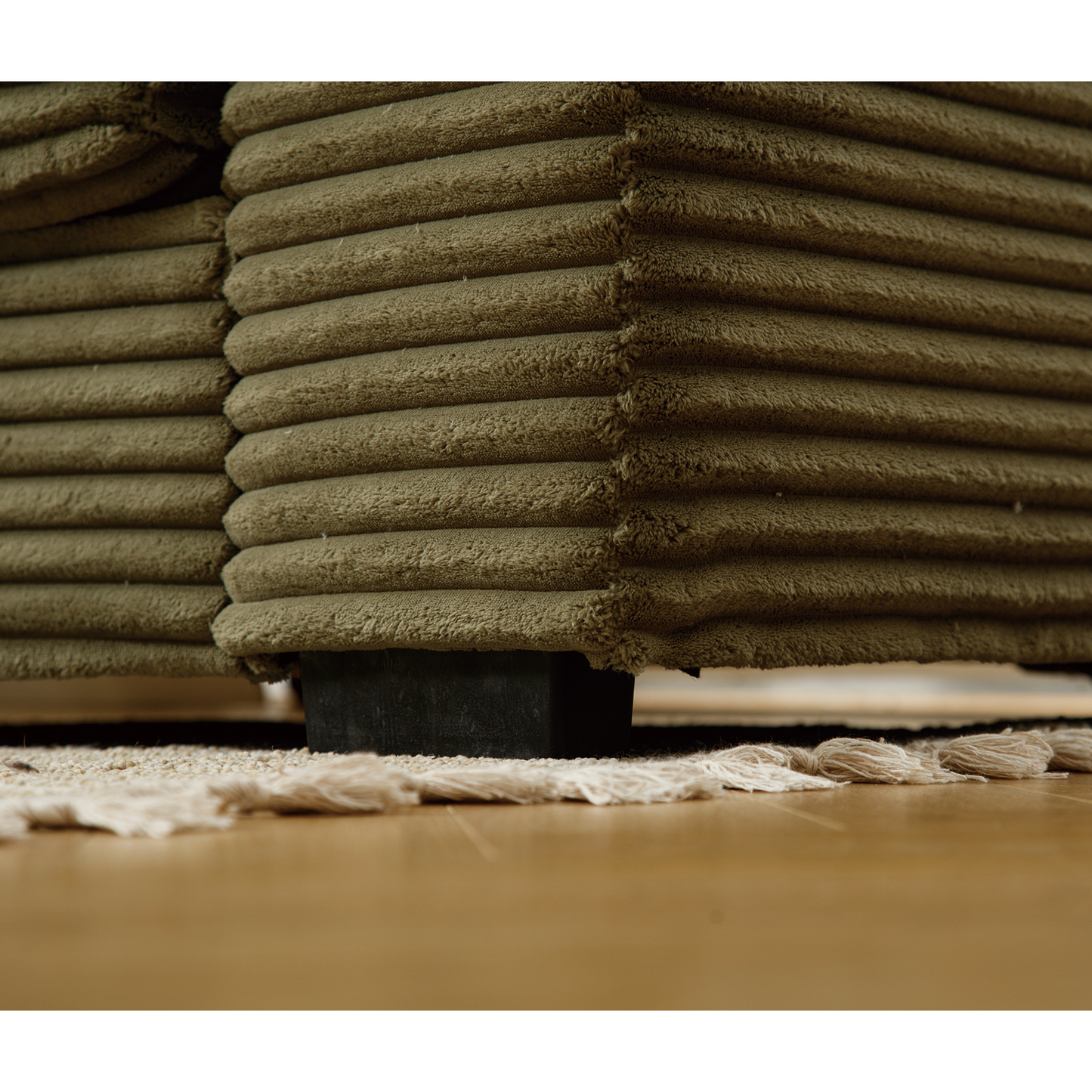 Textured olive corduroy sofa armrest detail with subtle sheen