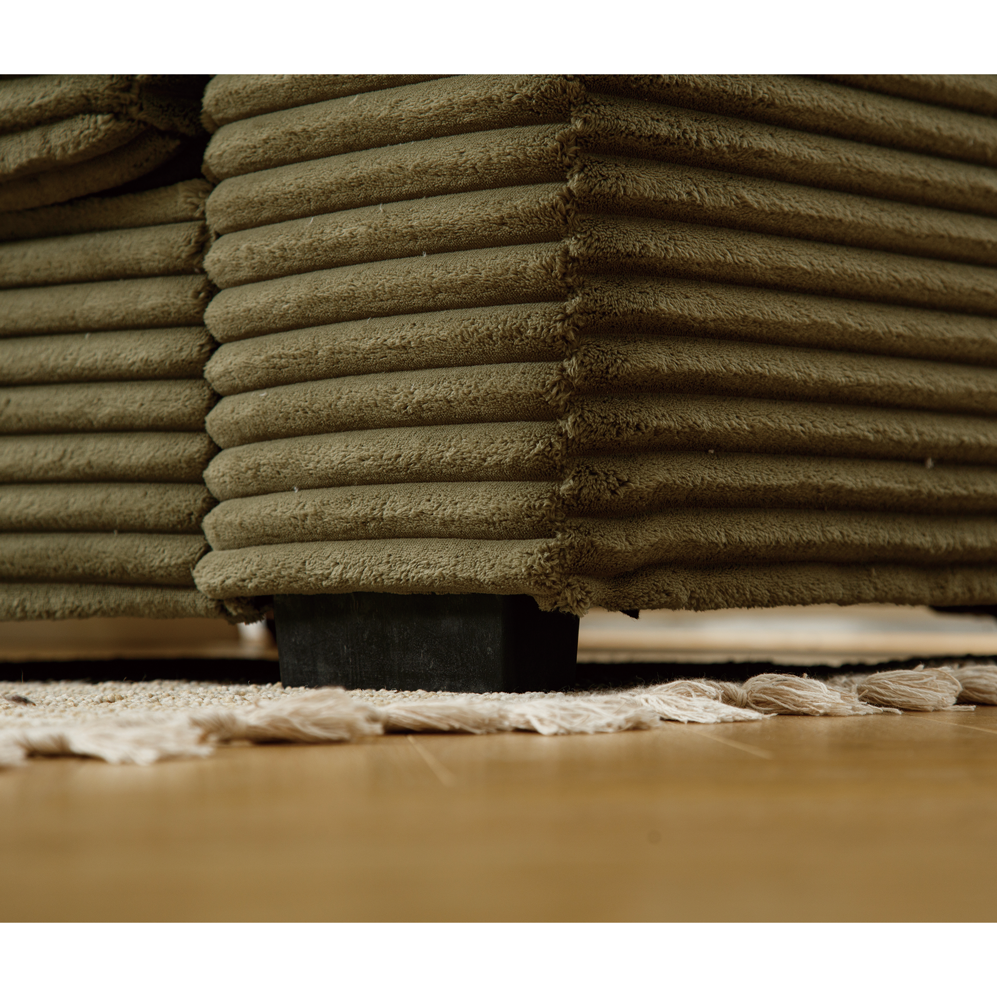 Textured olive corduroy sofa armrest detail with subtle sheen