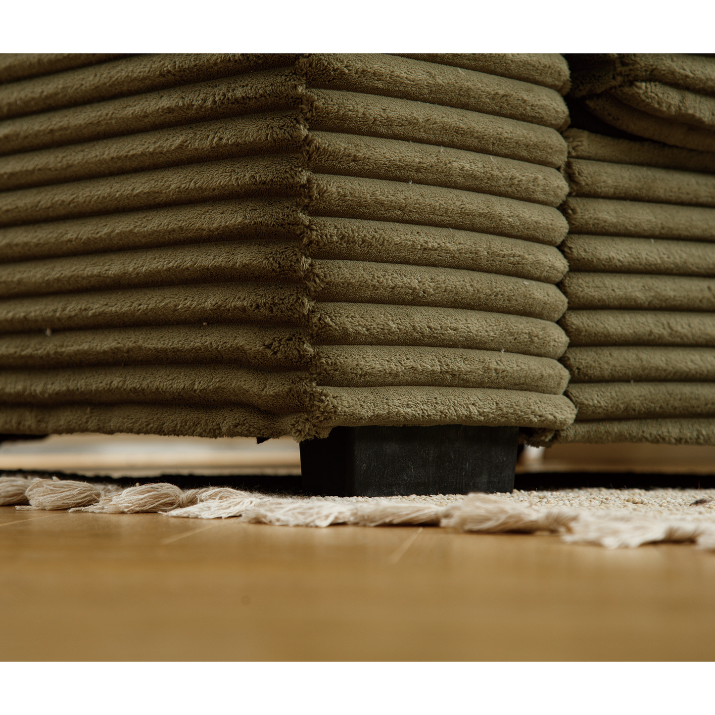 Closeup of a green corduroy sofa section with visible texture showcasing plush fabric