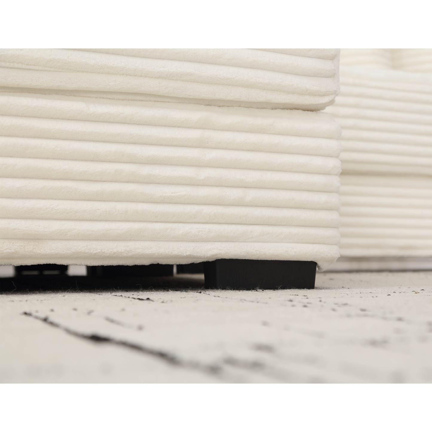 Closeup of plush cream corduroy fabric detail on a sofa showing horizontal texture