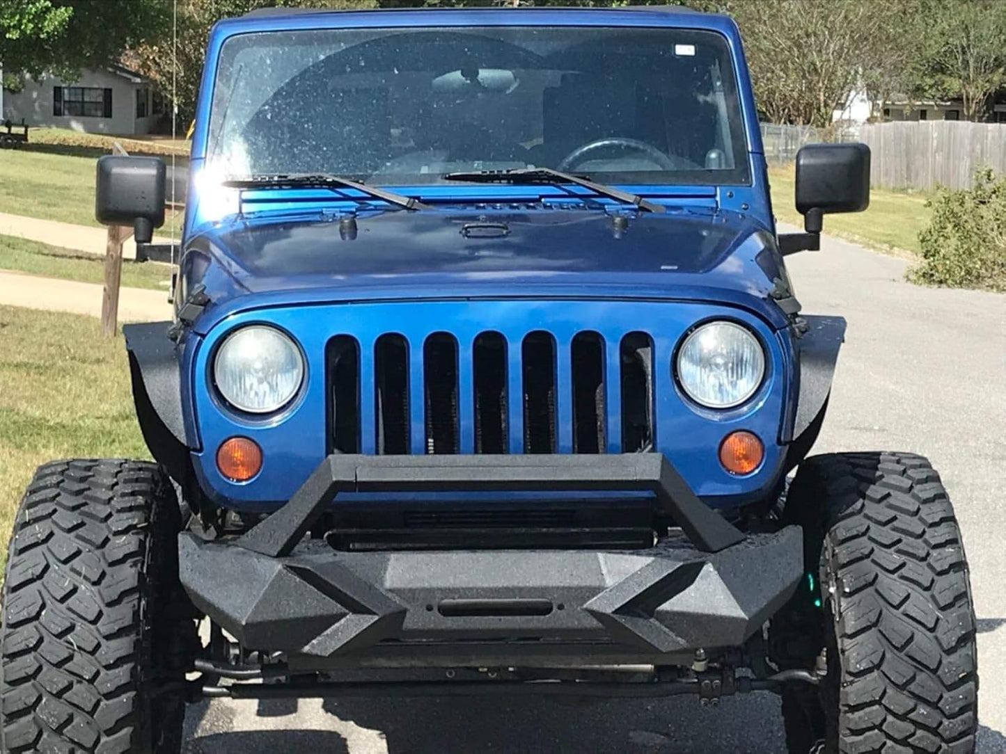 Front view of a metallic blue Jeep Wrangler with aggressive aftermarket tires