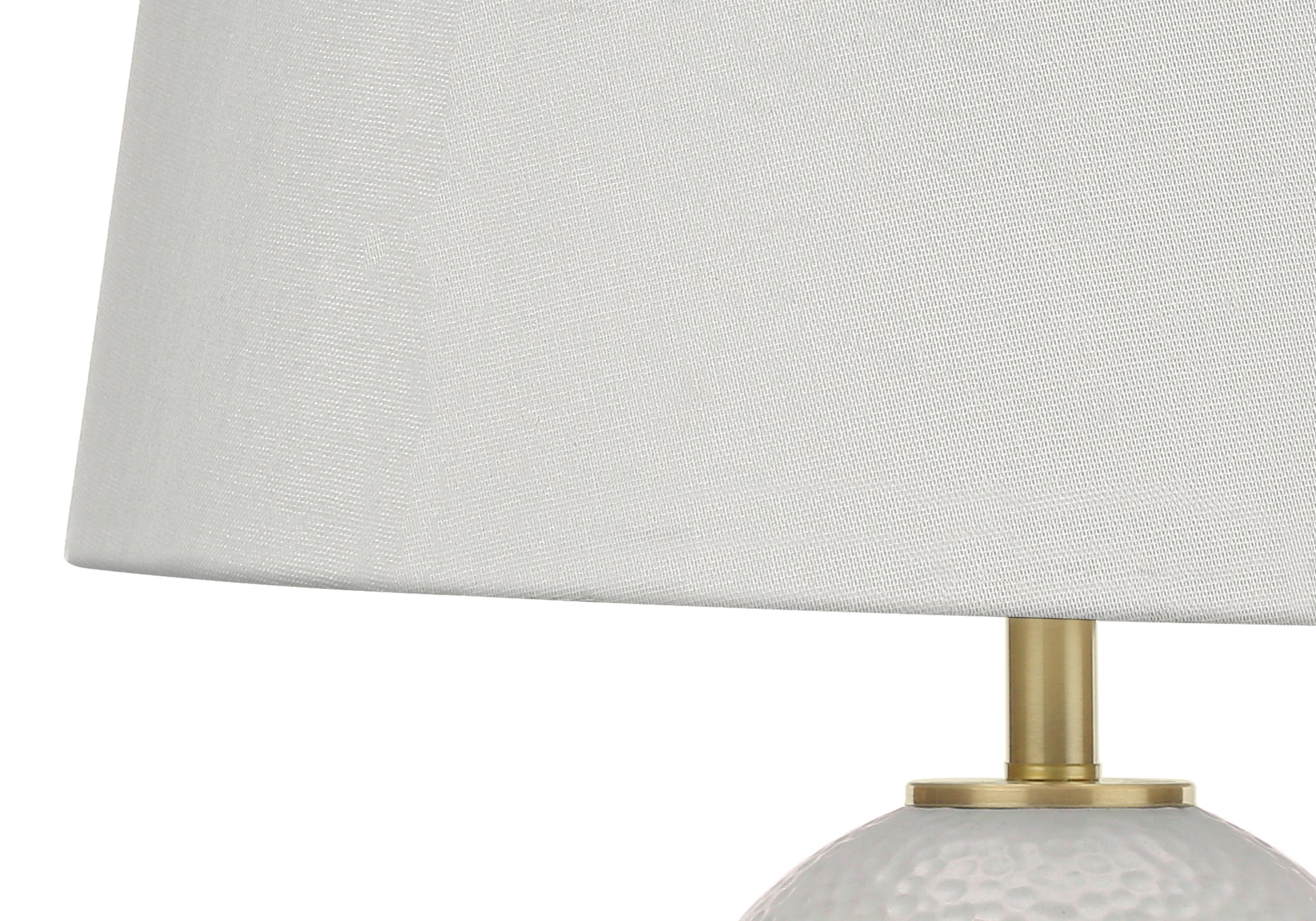 Closeup of a textured white fabric lampshade with a brass stand
