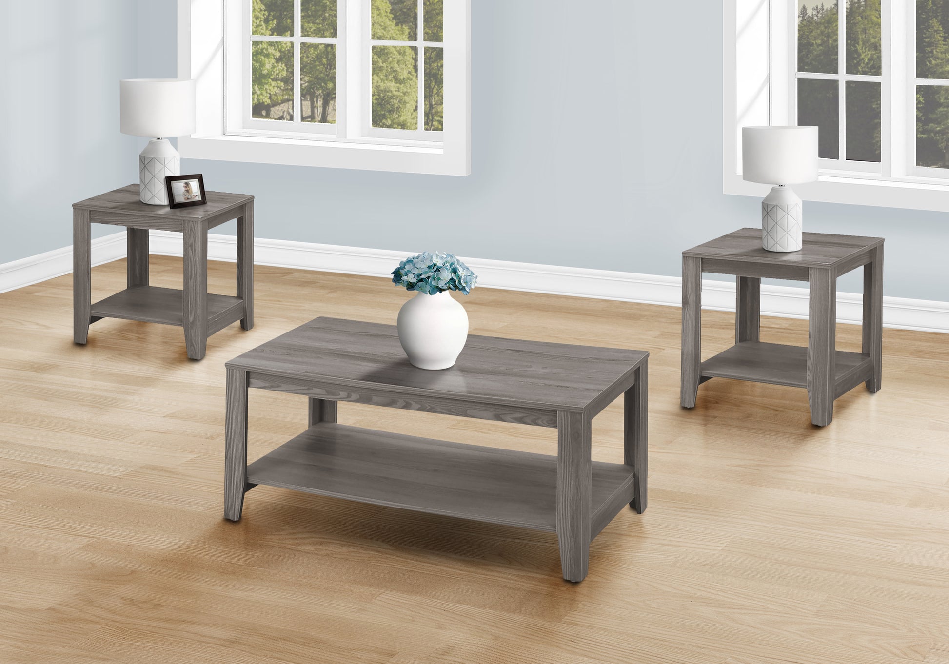 Gray wood coffee table with lower shelf and white vase of blue flowers