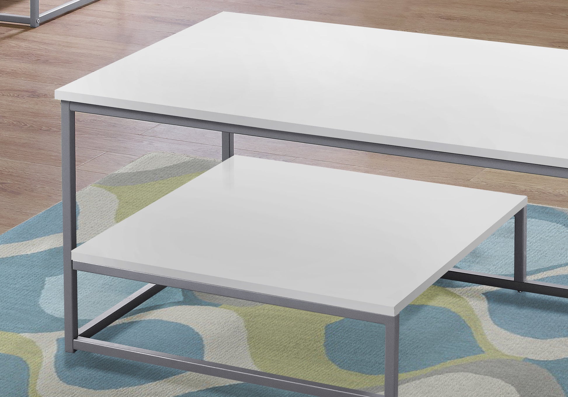 Modern white rectangular coffee table with gray metal frame nested on a colorful rug