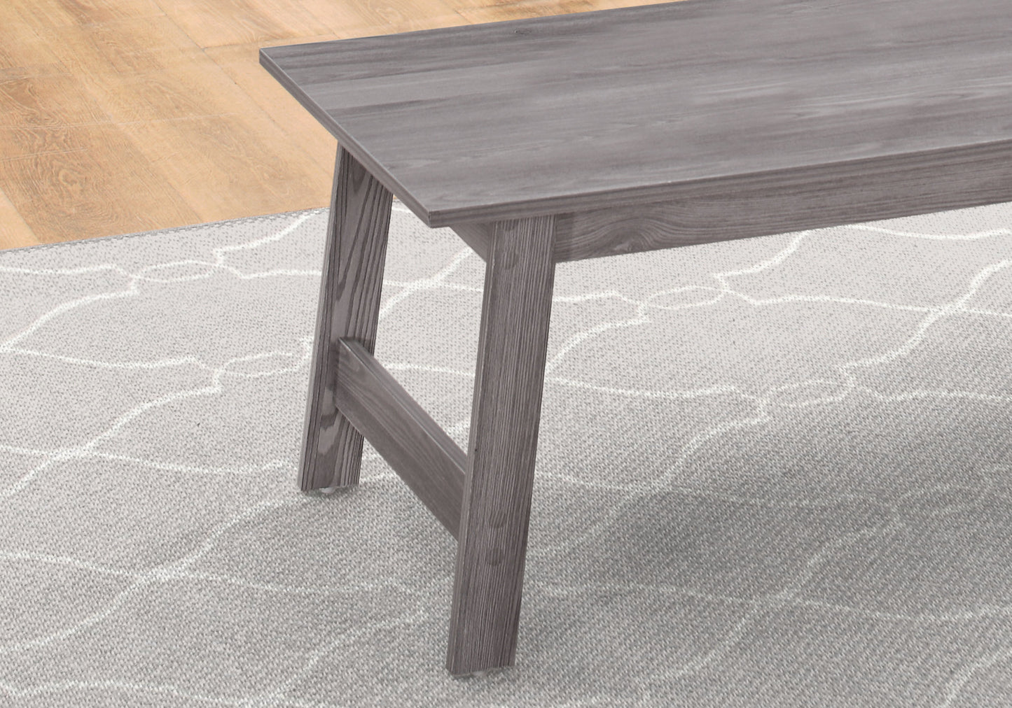 Distressed grey wood dining bench with angled legs on patterned rug