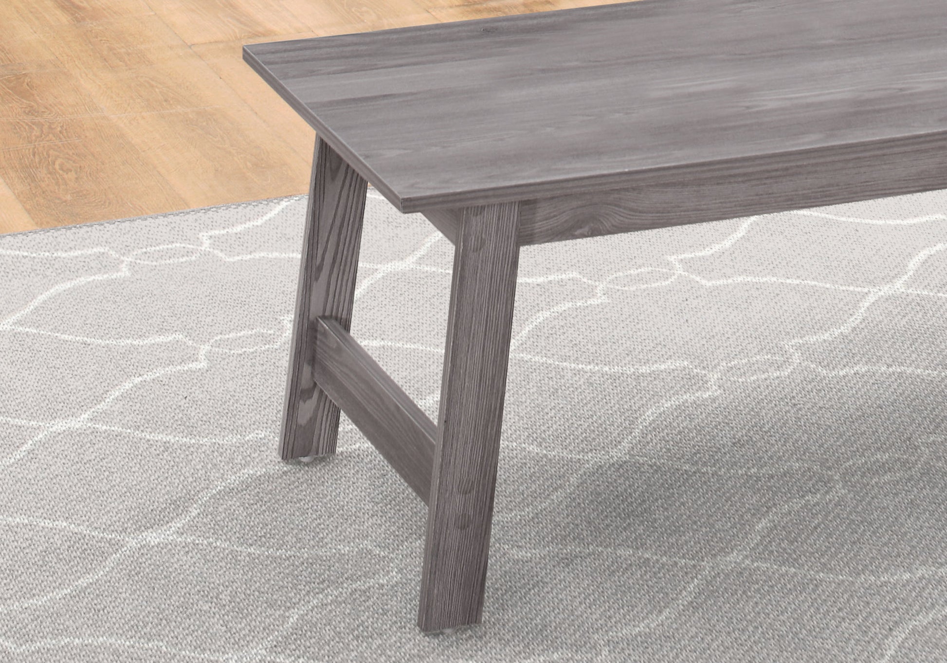 Distressed grey wood dining bench with angled legs on patterned rug
