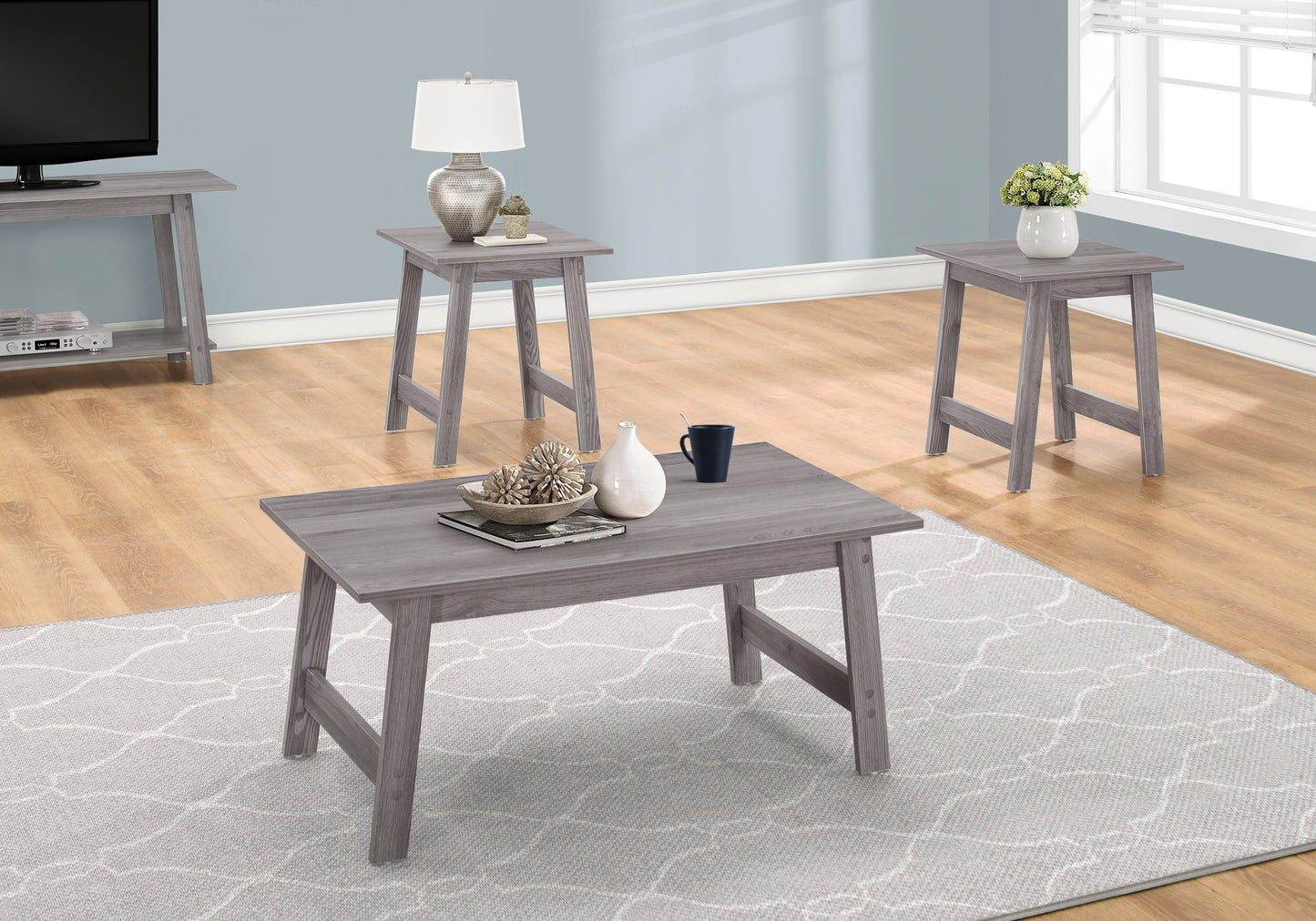 Grey modern coffee table with textured decor white vase and dark blue mug on a patterned rug