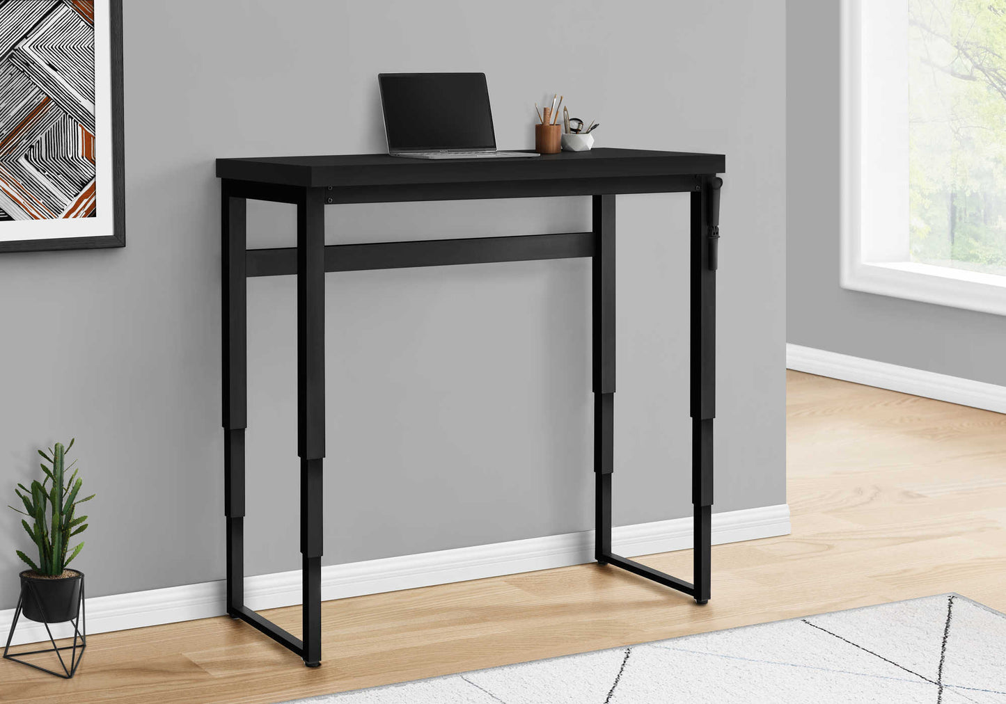 Sleek black metal desk with adjustable legs and a laptop