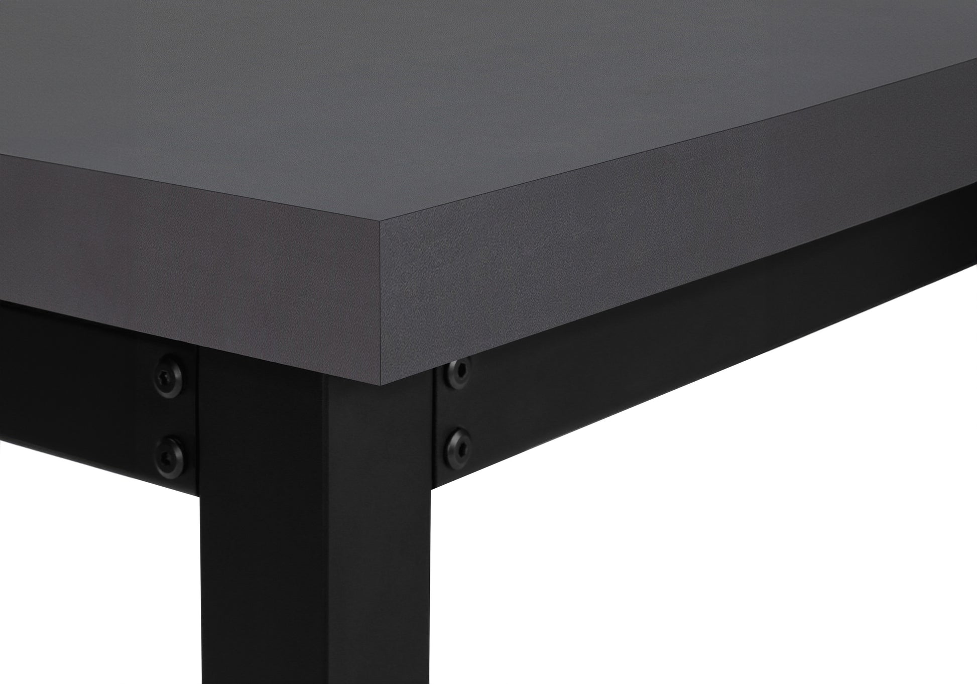 Closeup of a dark grey laminate desk edge with black metal legs and visible screws