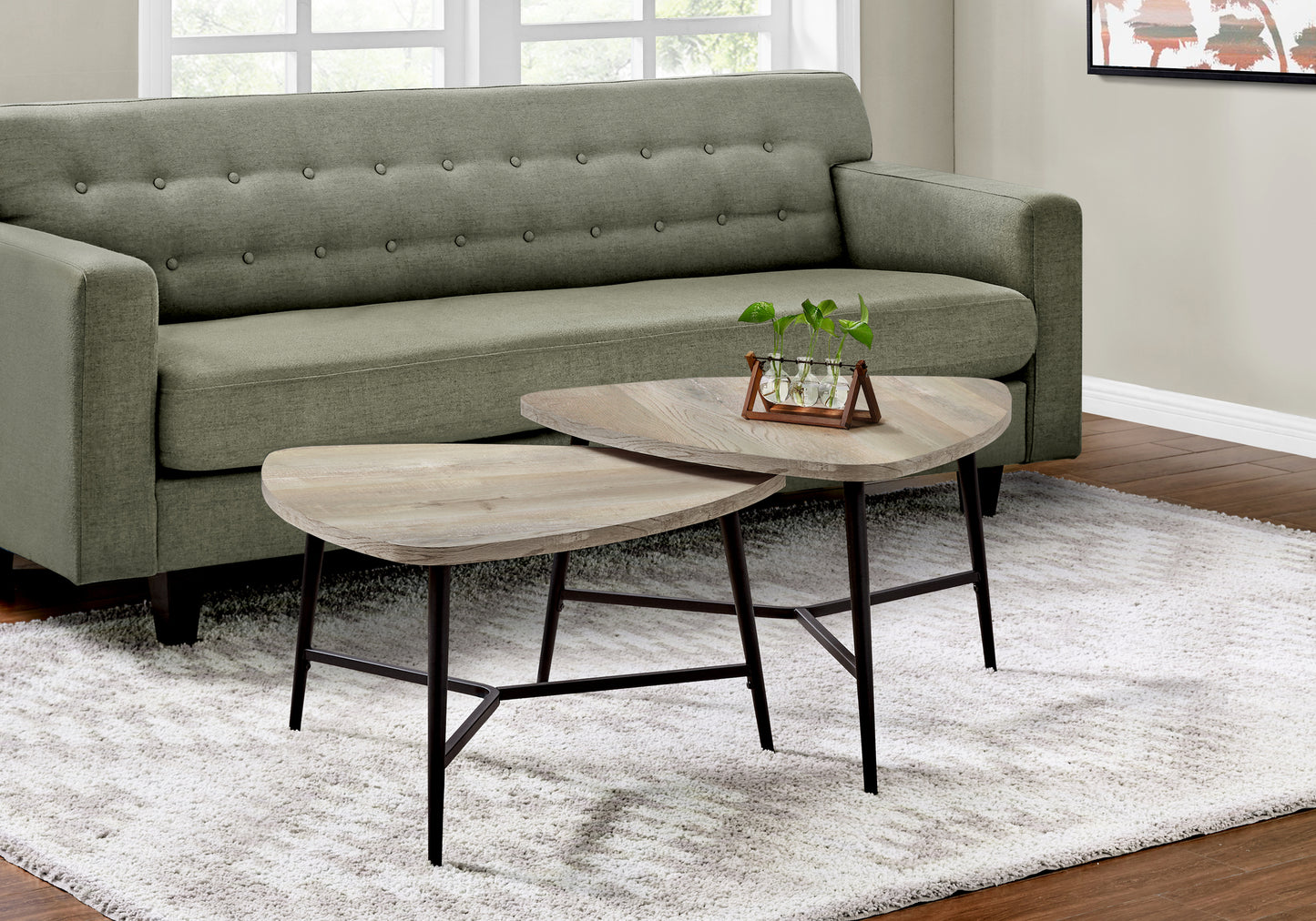 Two modern distressed wood nesting coffee tables with black metal legs on a textured rug