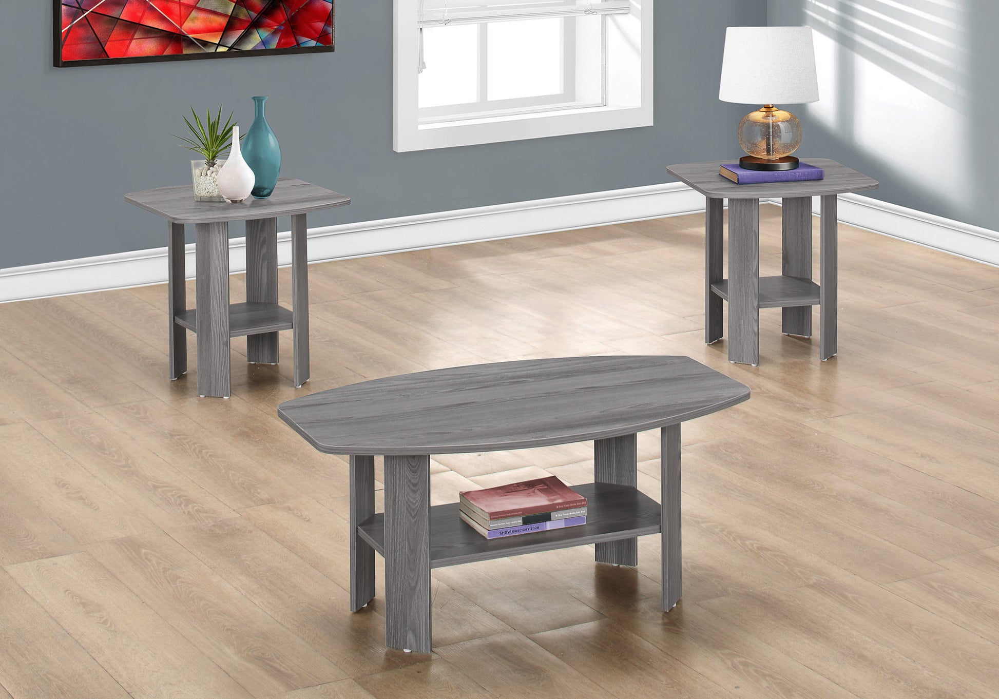 Gray wood oval coffee table with lower shelf holding two books